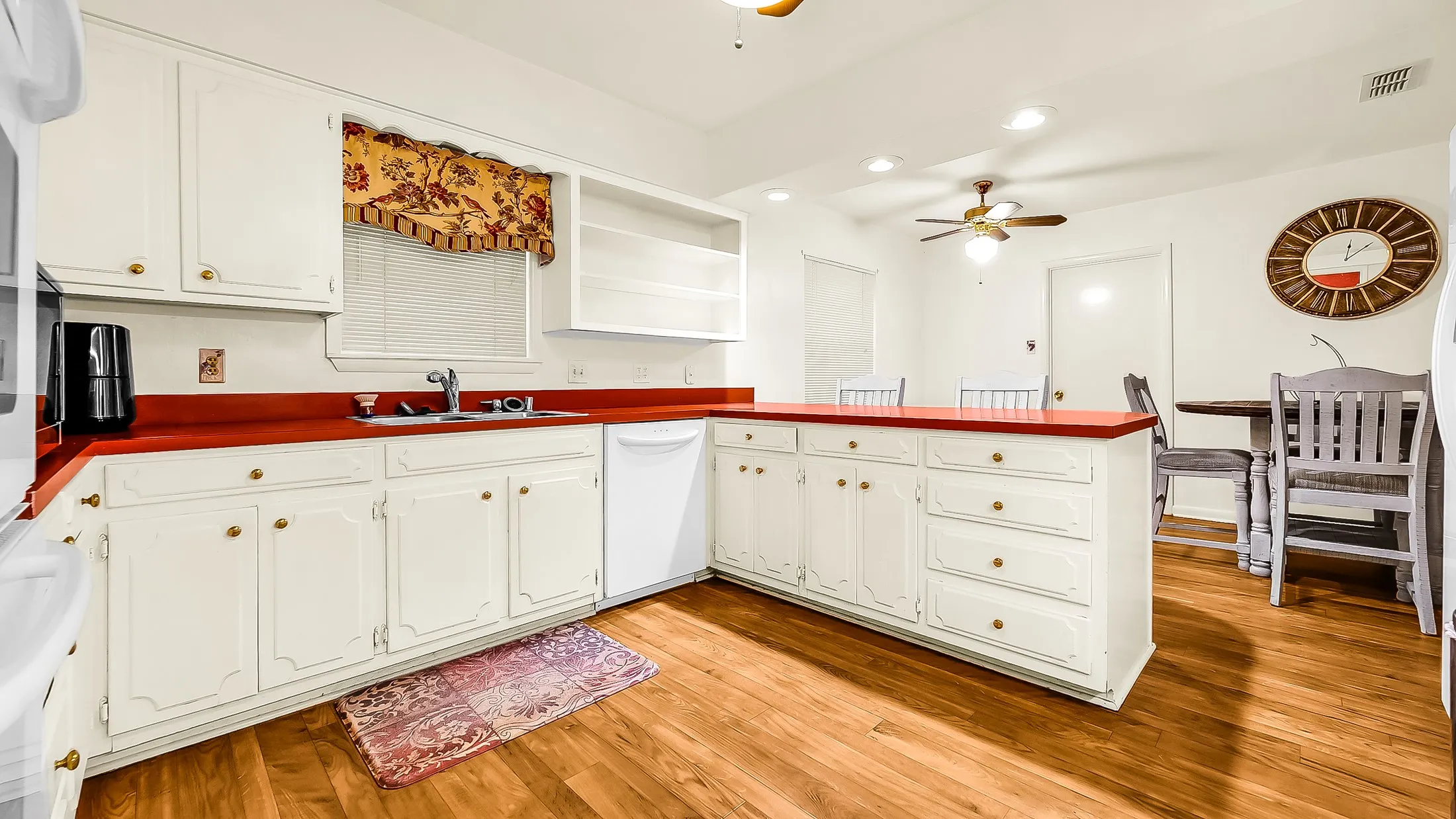 Kitchen featuring white cabinetry, red countertops, and wood-finish flooring
