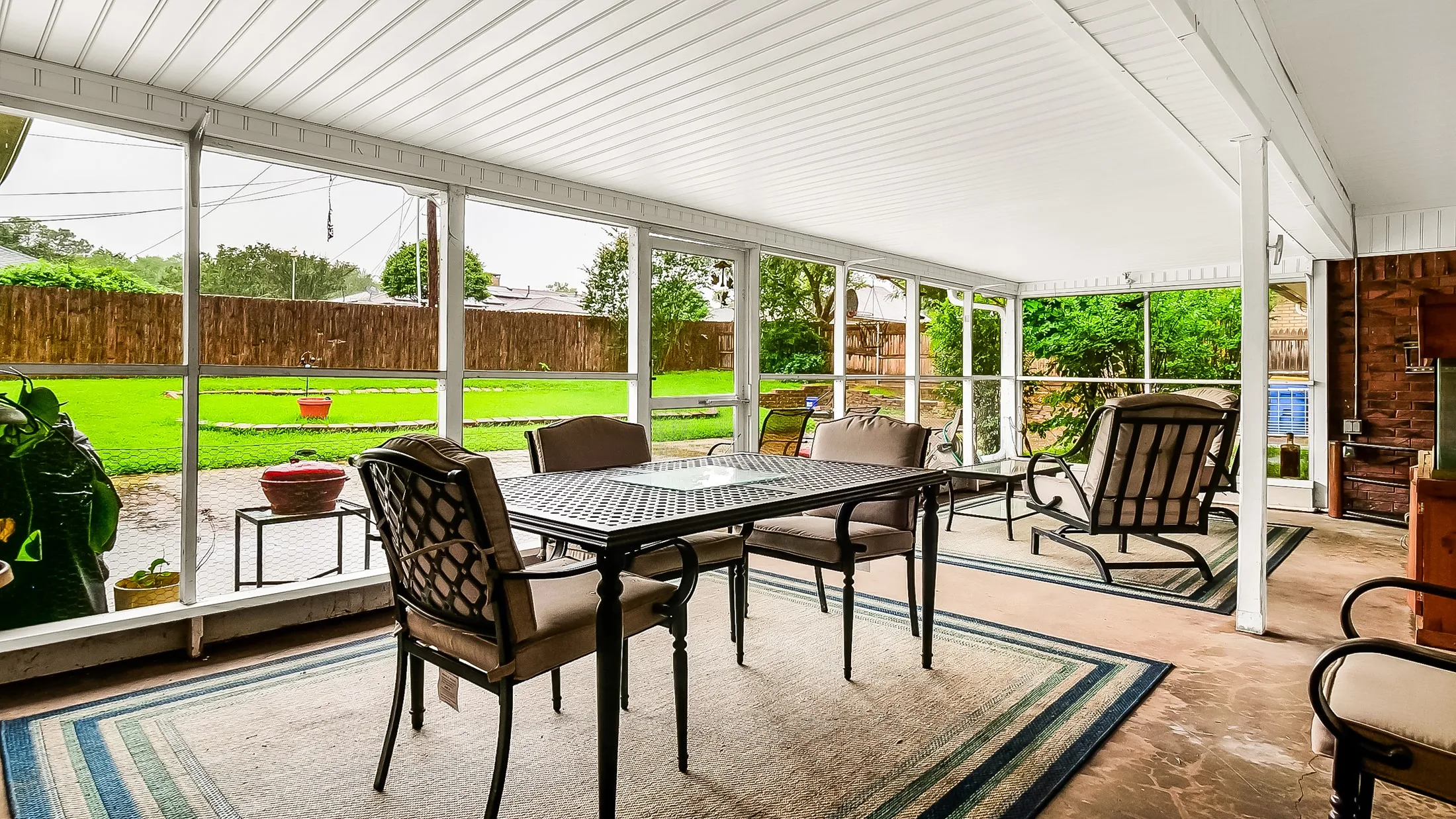 Screened patio with a white paneled ceiling, concrete flooring, and a stone accent wall