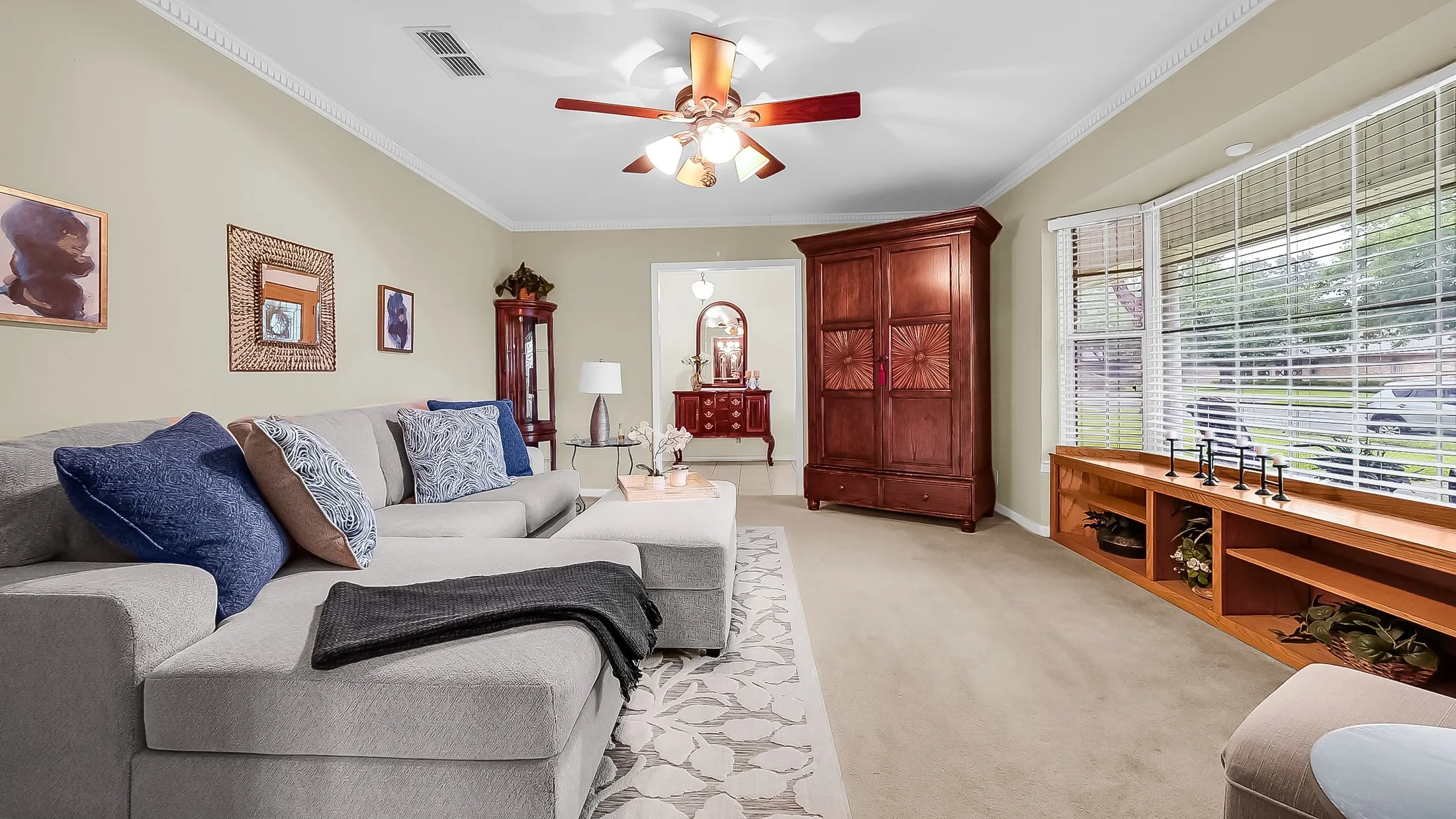 Spacious living area featuring neutral-toned walls, crown molding, and carpet flooring