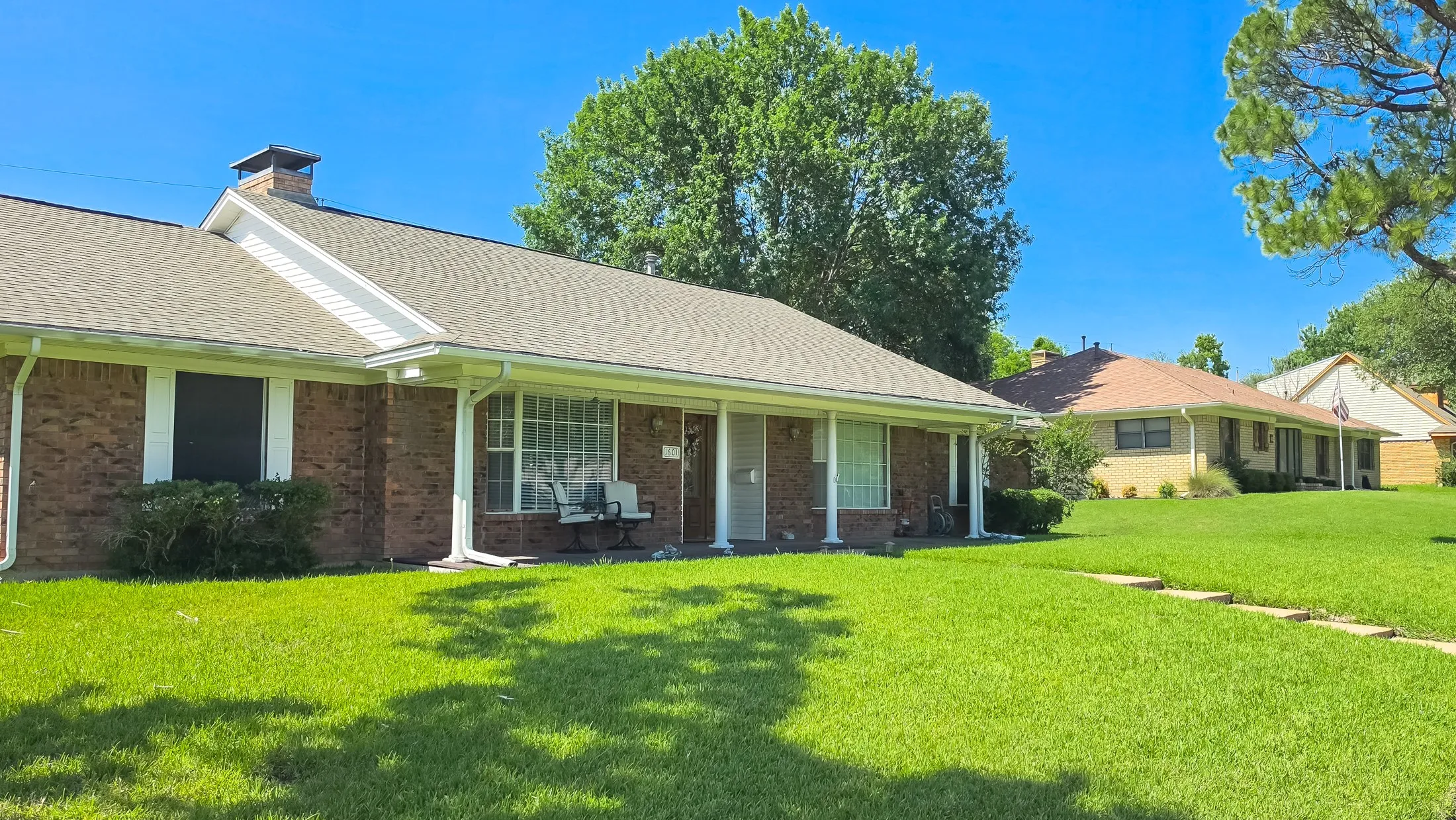 Brick exterior with a covered porch entry, chimney, and a shingle roof