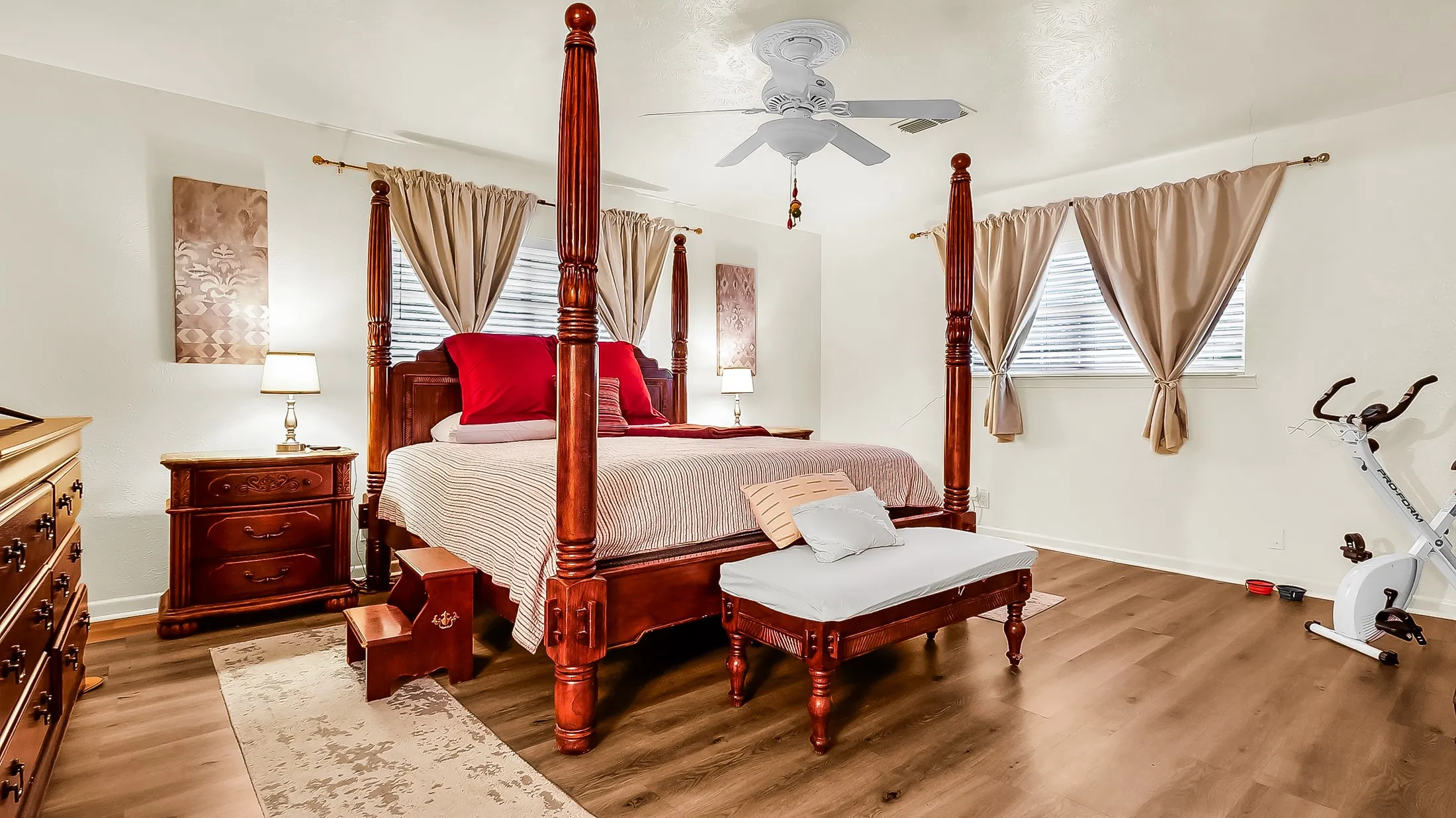 Spacious room featuring wood-finish flooring, light-colored walls, and a ceiling fan with integrated lighting