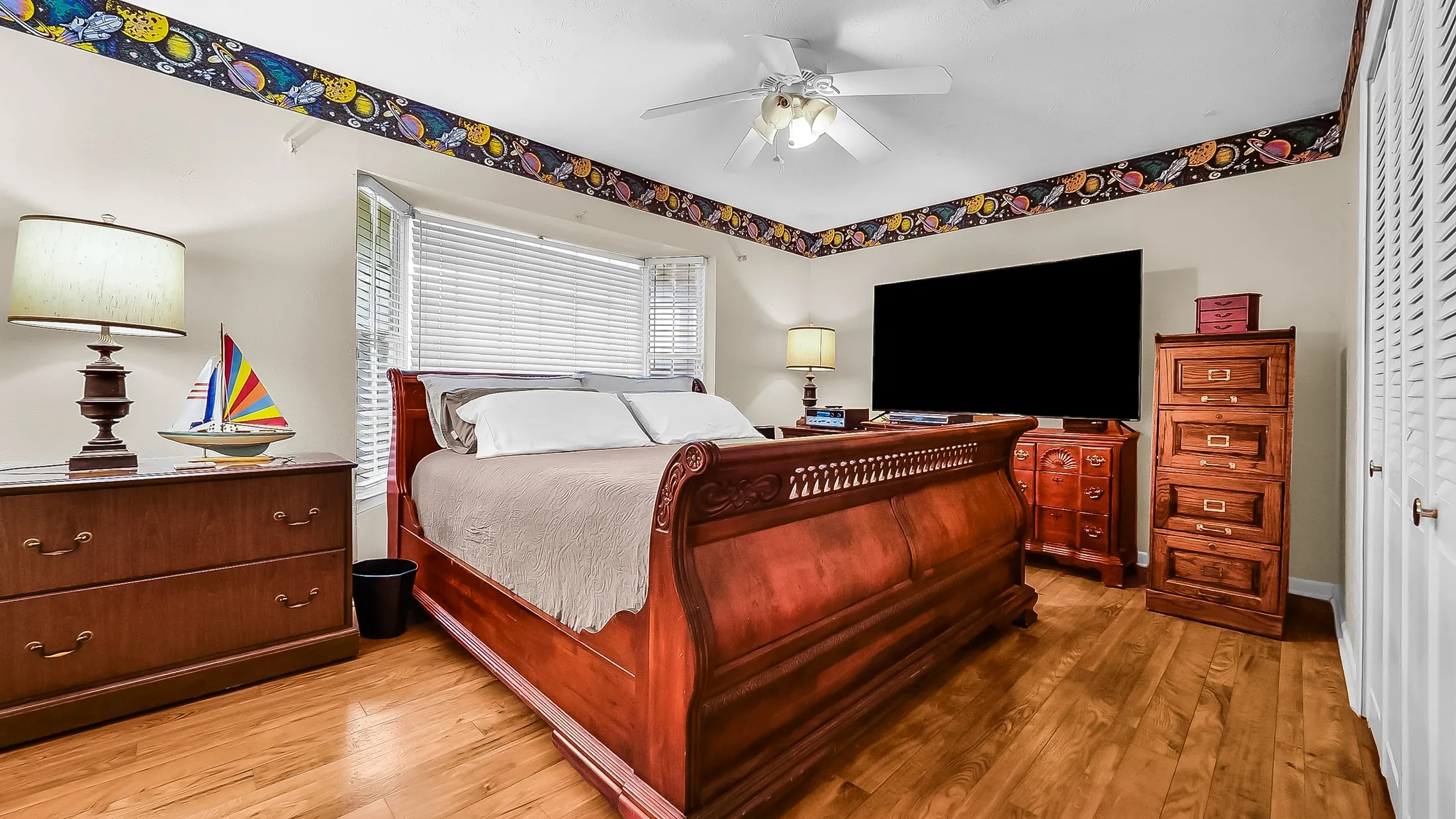 Bright room featuring wood-finish flooring, a ceiling fan, and a window with blinds