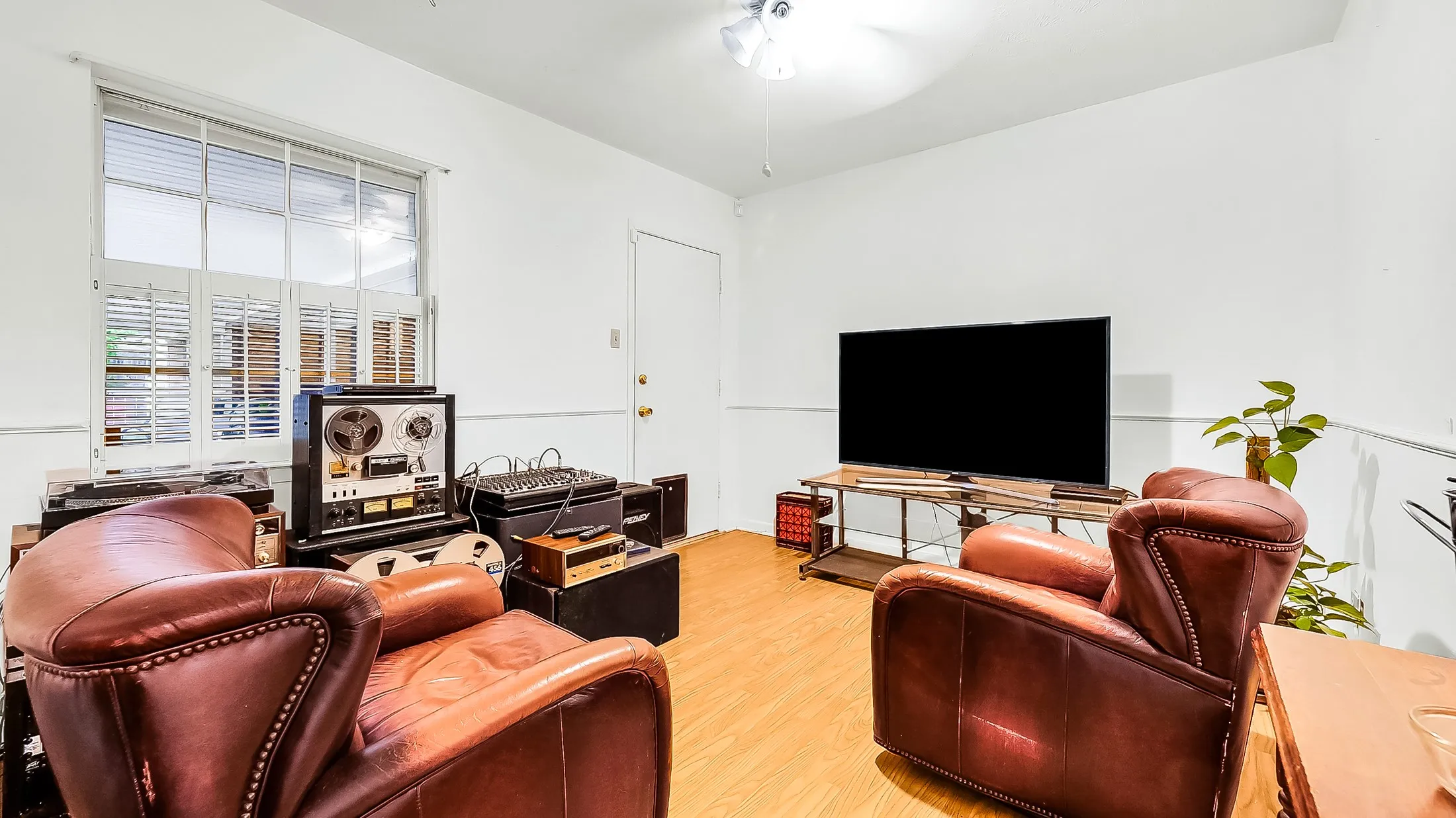 Bright interior space featuring a window with white shutters, crown molding, and wood-finish flooring