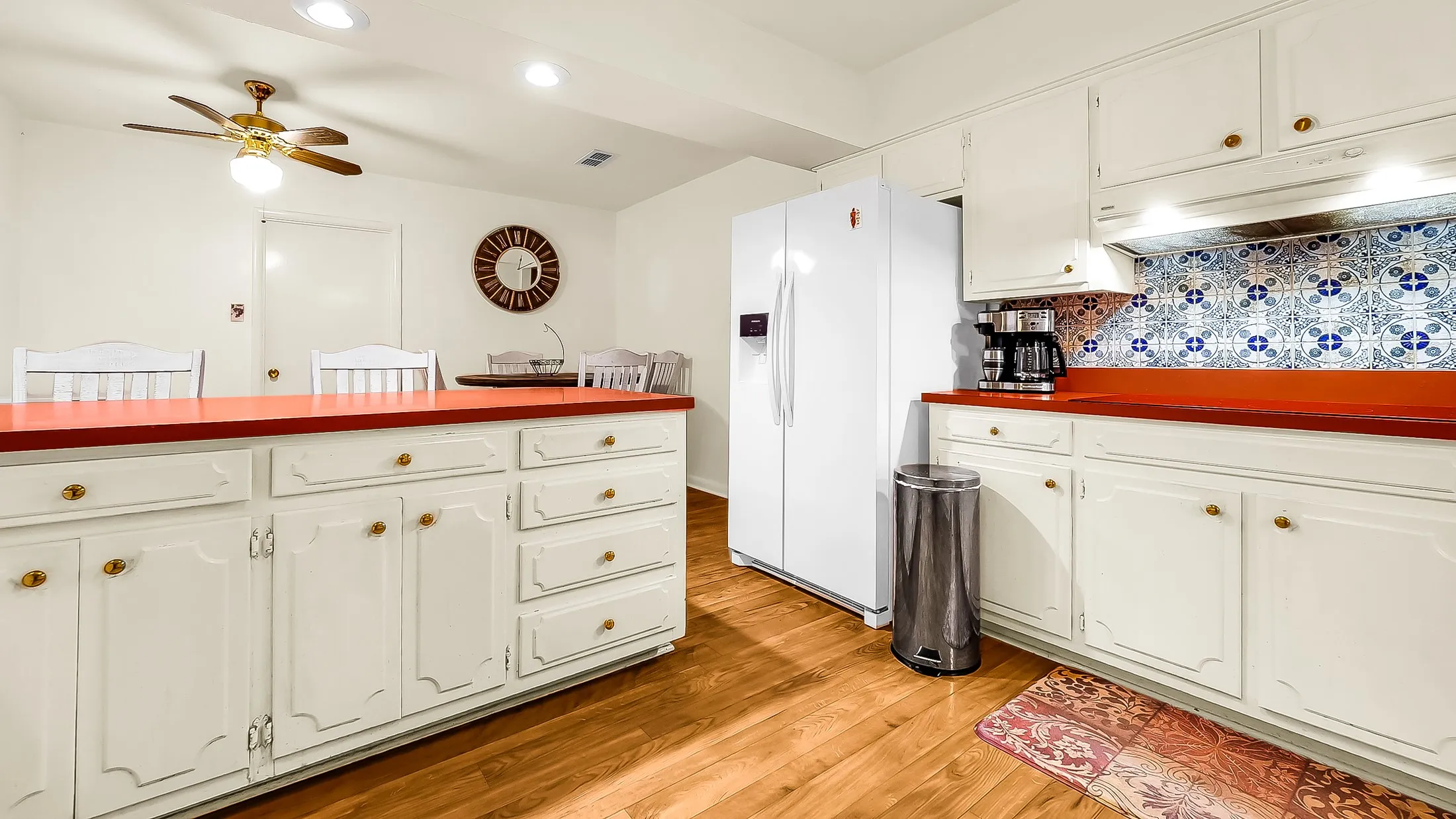 Kitchen featuring wood-finish flooring, white cabinetry with gold-tone hardware, and red countertops