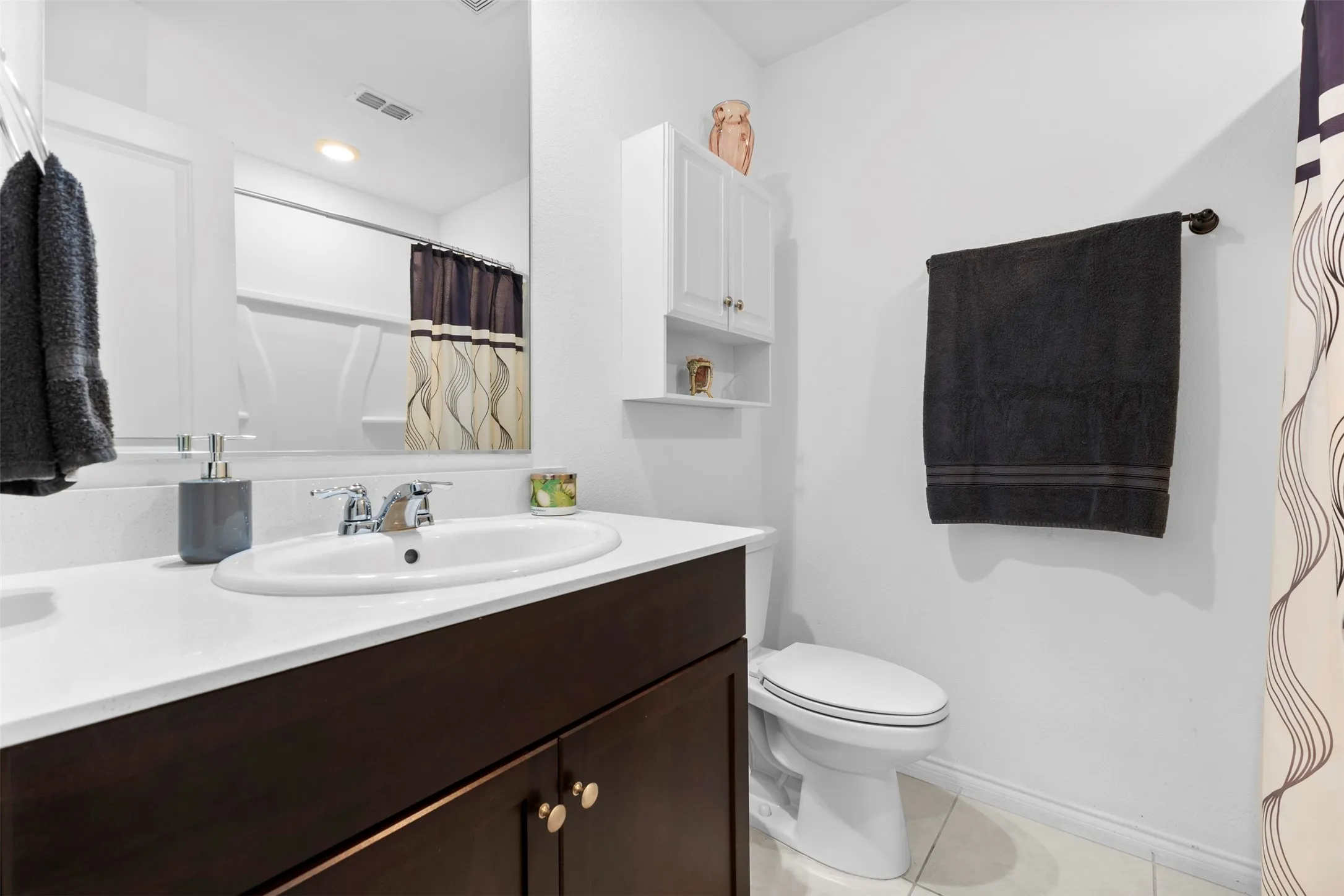 Bathroom featuring a single vanity with dark wood-finish cabinetry, a white countertop, and a chrome faucet