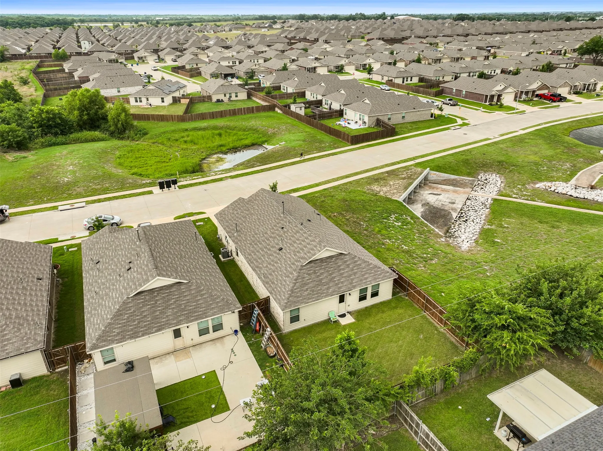 Two single-story residences featuring light-colored exteriors and dark shingle roofs, each with a fenced backyard