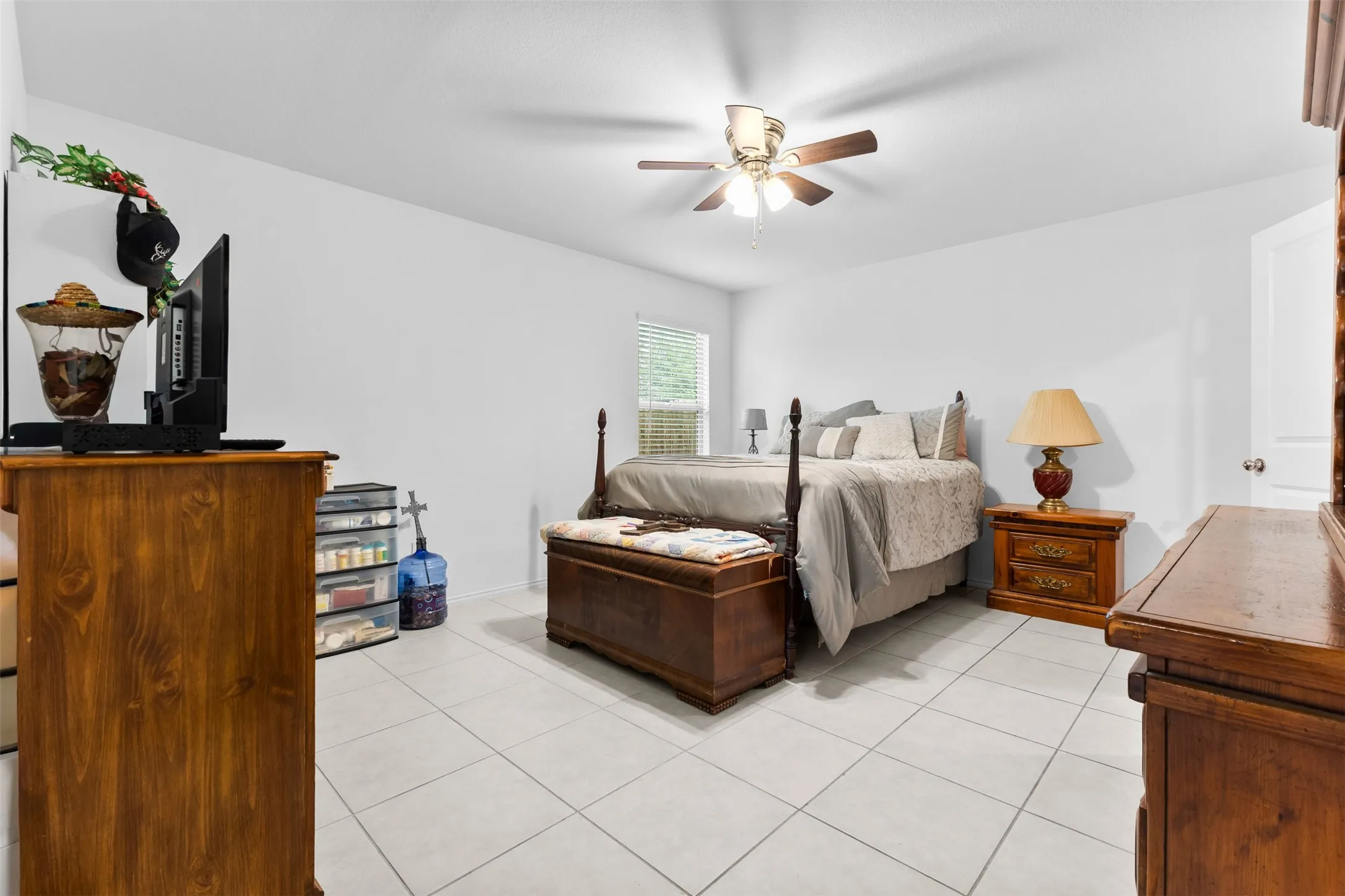 Spacious room featuring light-toned tile flooring, a ceiling fan with integrated lighting, and white painted walls