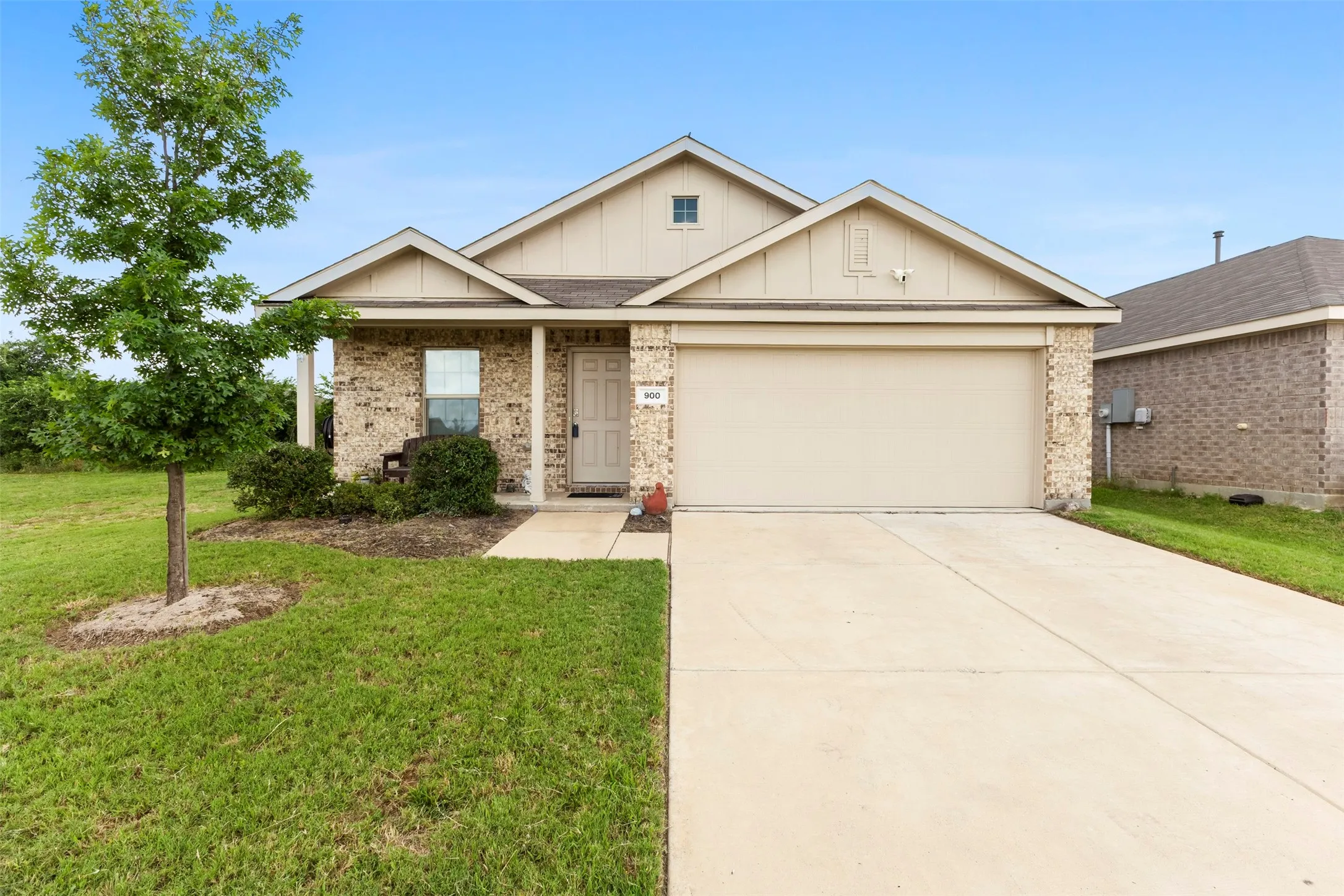 Brick veneer exterior with a covered entry, attached garage, and concrete driveway