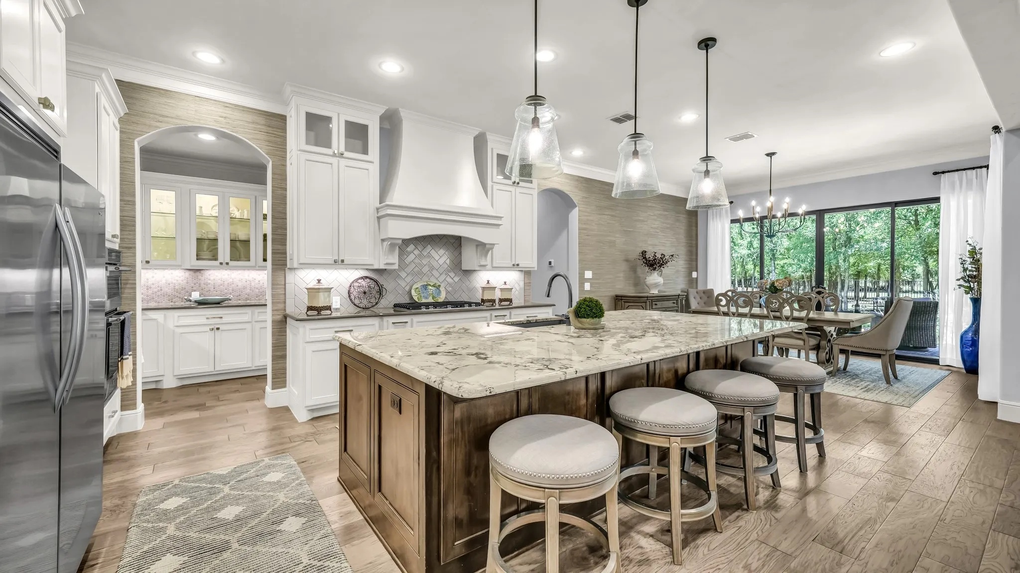 Kitchen and dining room. Through the left door is a sizable butler's pantry and an enormous food pantry. Another sliding glass door encompasses the dining room wall. This sliding glass door leads to the "grilling-dining" patio.
