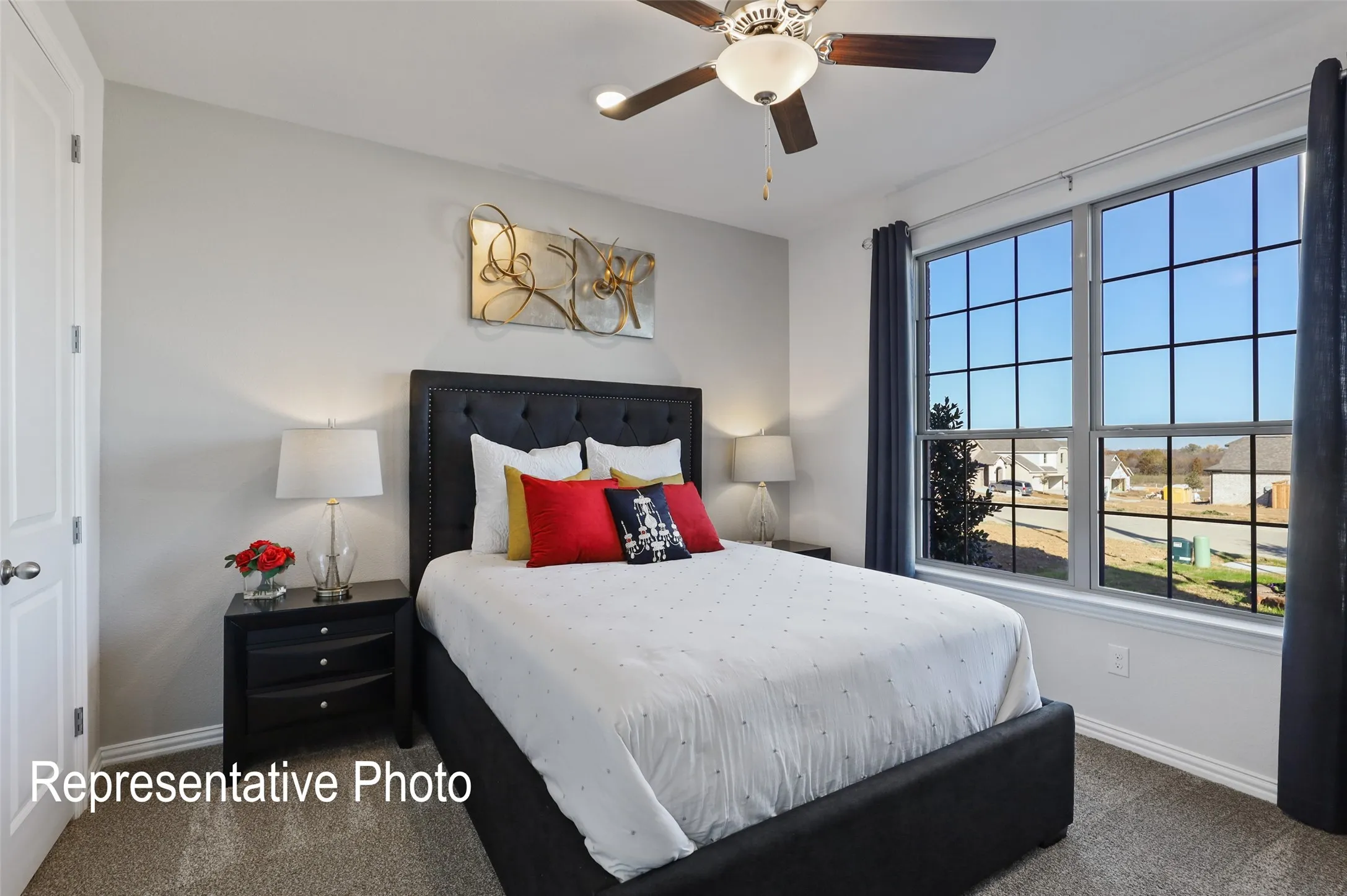Bedroom featuring light gray walls, plush gray carpeting, a multi-pane window with grid accents, and a ceiling fan with integrated lighting