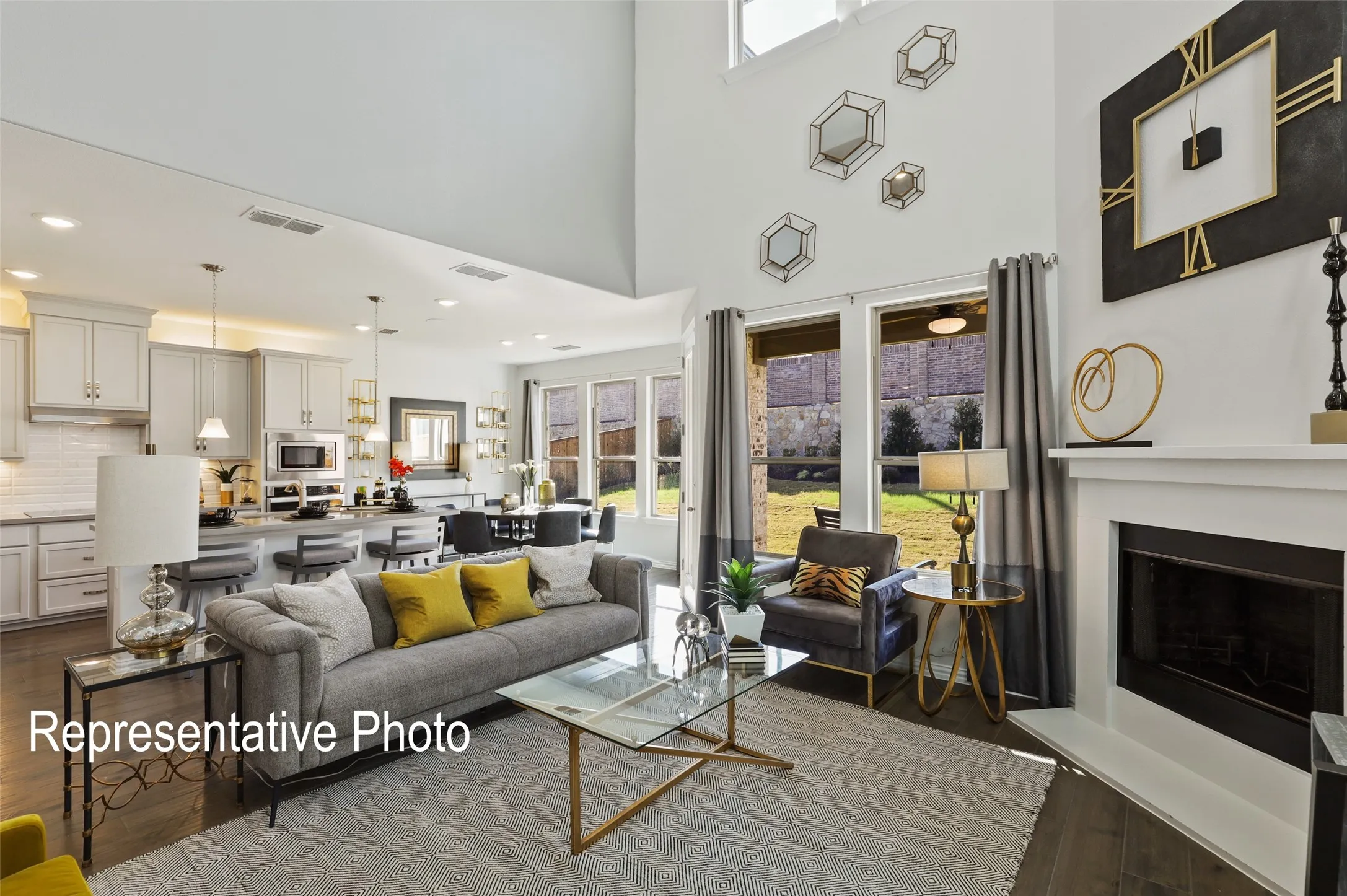 Spacious open-concept living area featuring high ceilings, wood-finish flooring, a contemporary fireplace, and abundant natural light from multiple windows