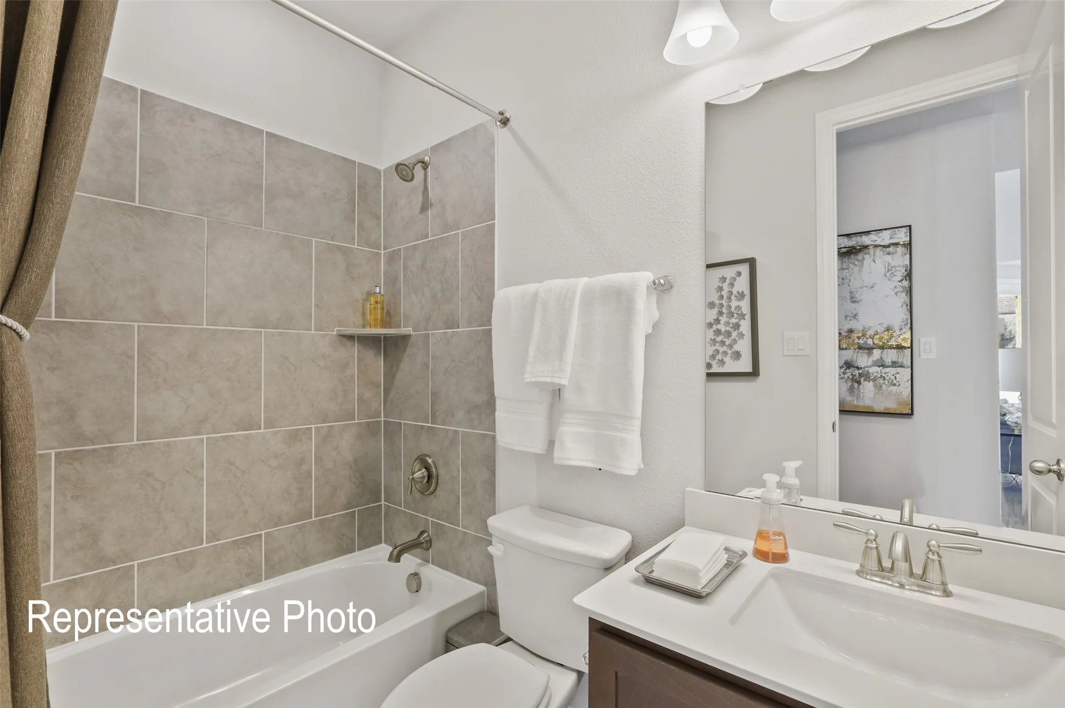 Bathroom featuring a built-in bathtub with subway tile surround, white vanity cabinet with countertop, and a large wall-mounted mirror