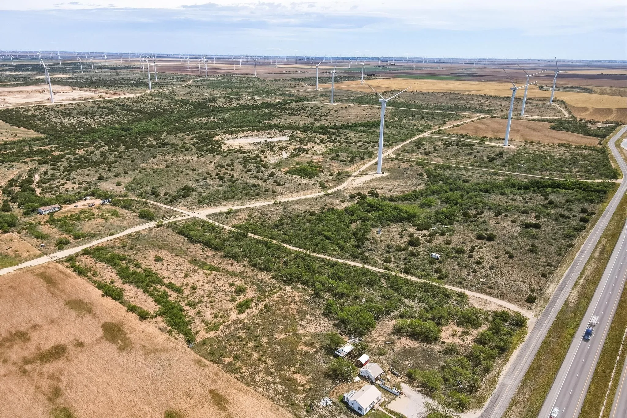 Expansive aerial property featuring significant acreage with scattered green foliage and brown earth