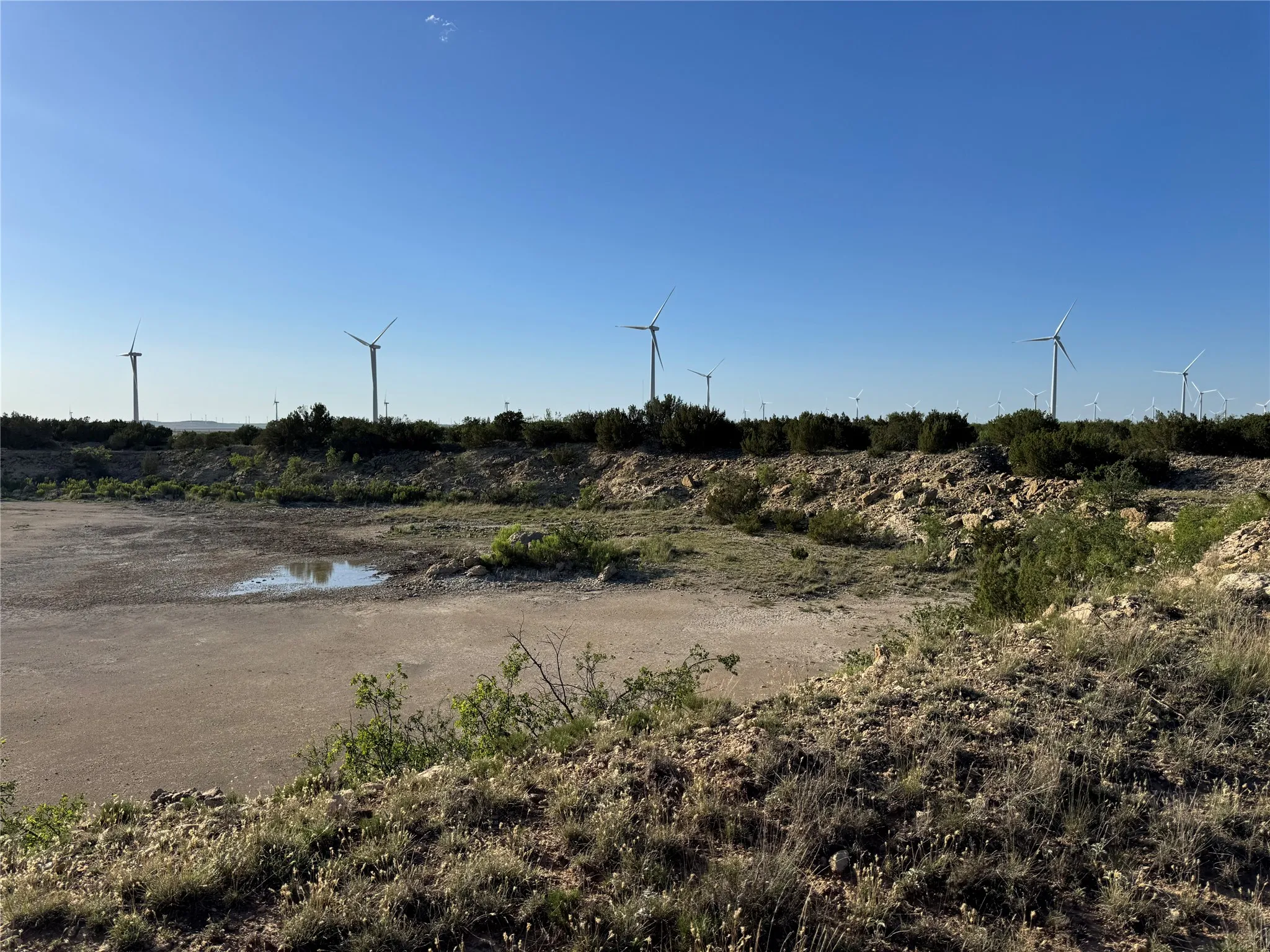 Expansive land parcel featuring natural terrain, low-growing vegetation, and a clear sky overhead