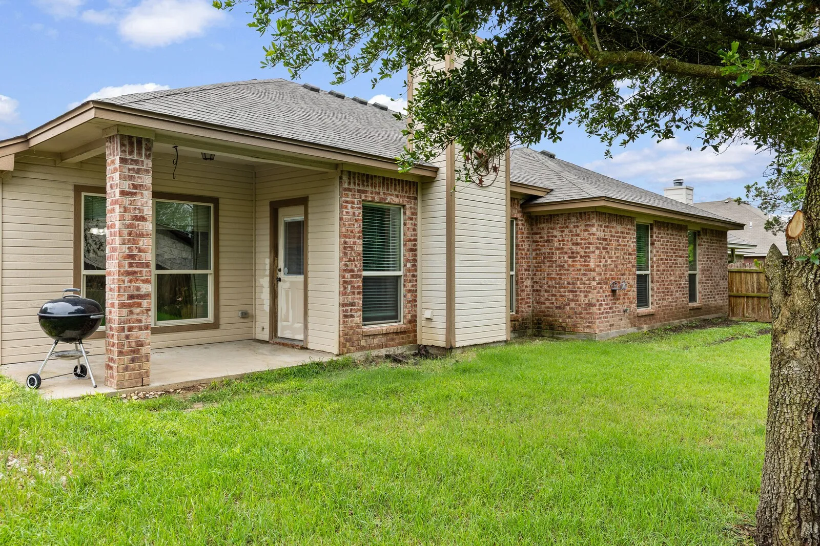Expansive backyard with a covered patio, brick columns, and a full brick exterior