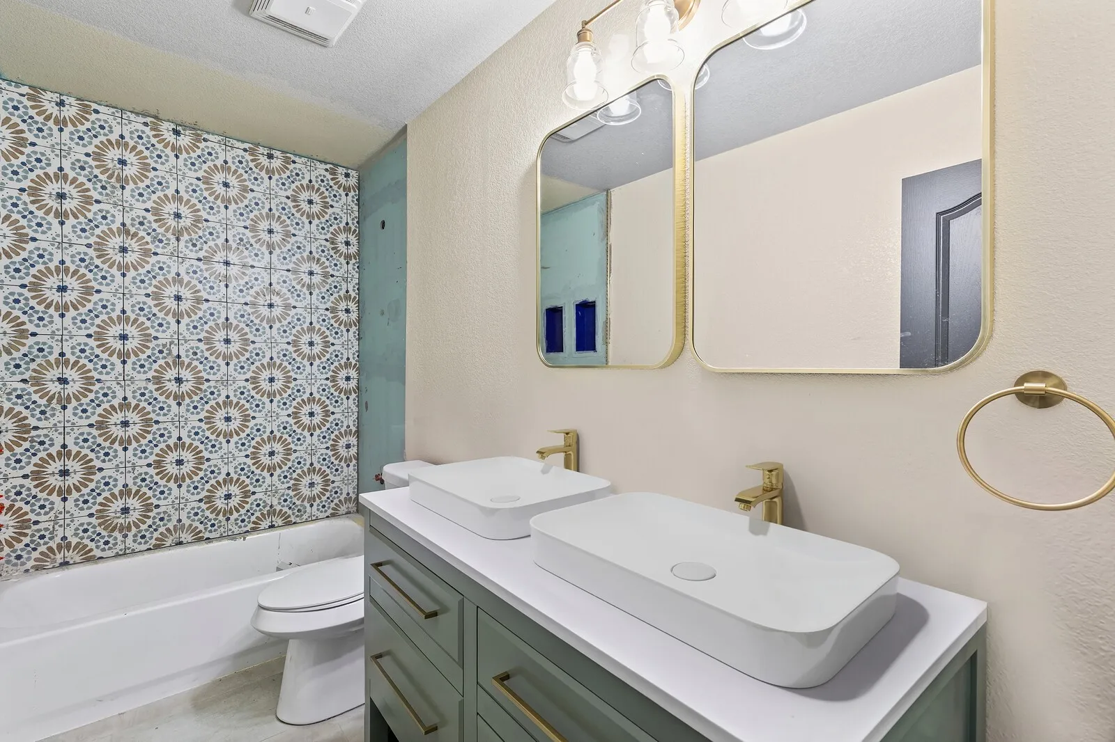 Double vanity with vessel sinks, gold-finish fixtures, and gold-framed mirrors