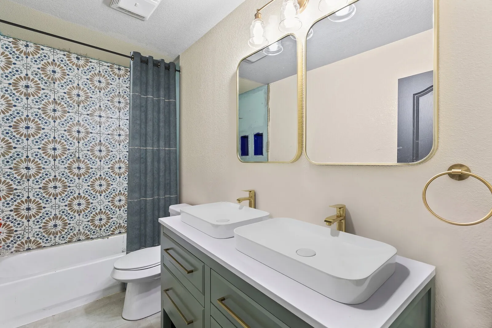 Bathroom featuring a dual vanity with rectangular vessel sinks, gold-finish faucets, and framed mirrors