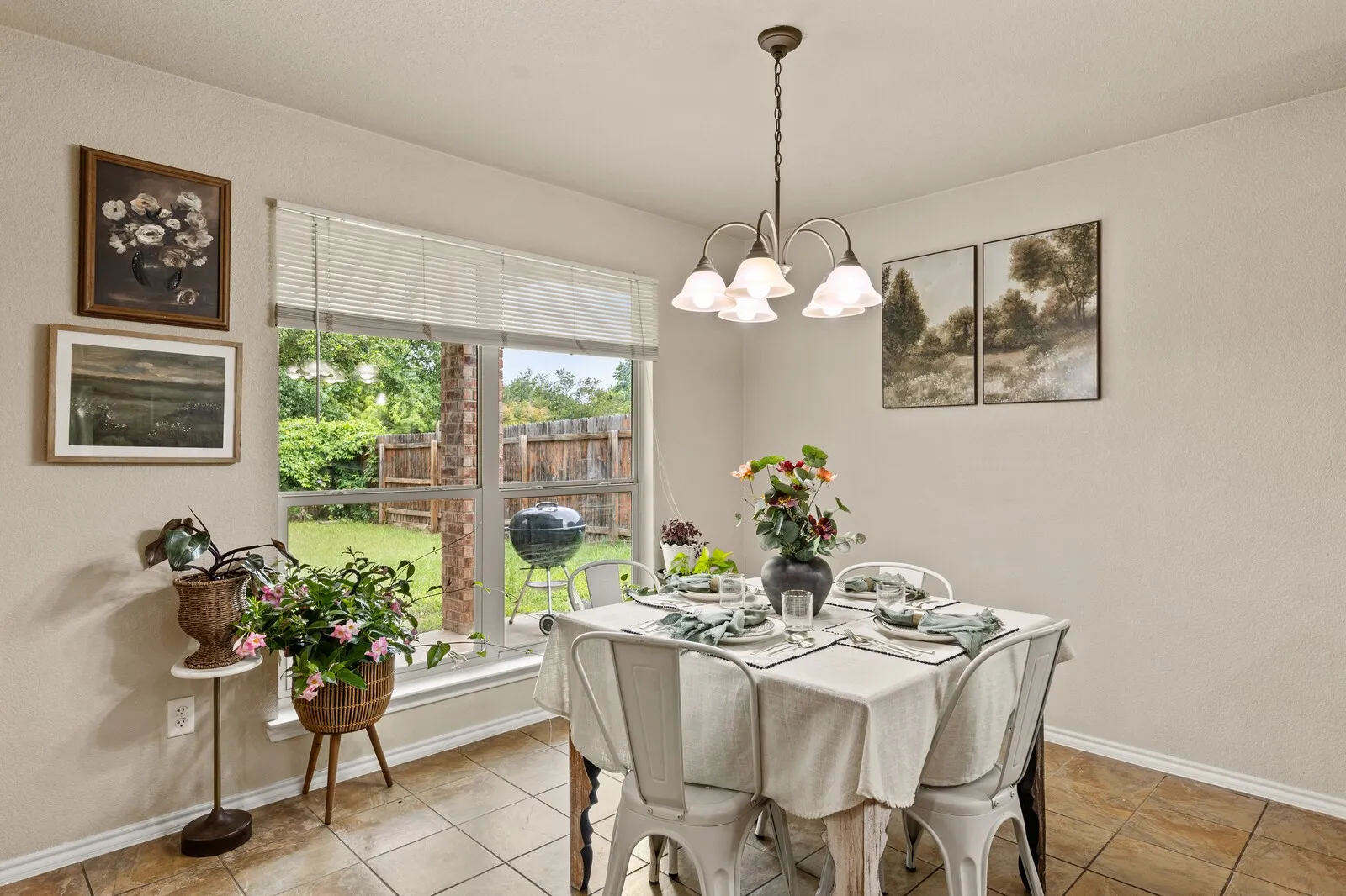 Dining space featuring a window overlooking the backyard, tile flooring, and a decorative chandelier