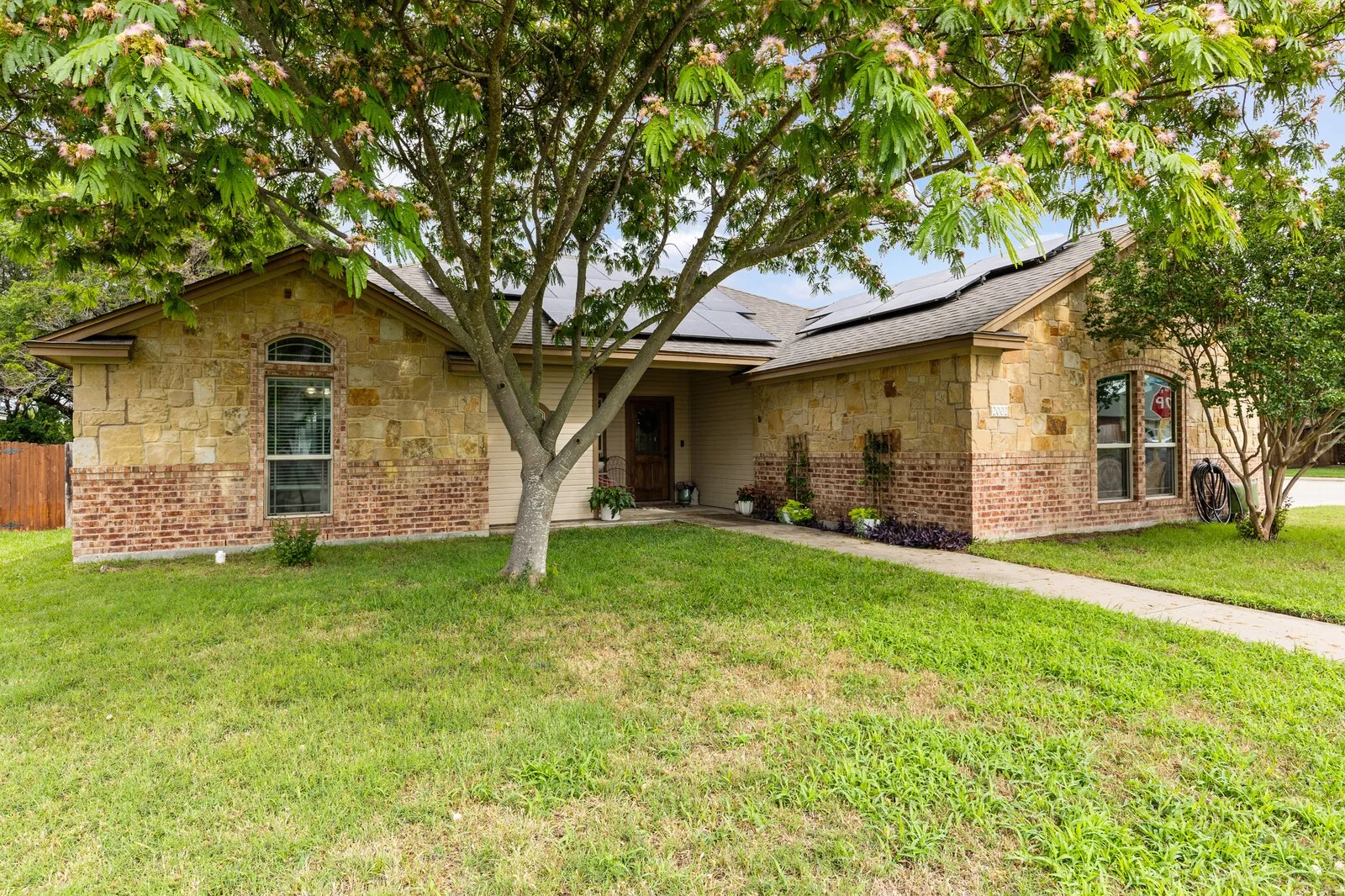 Stone and brick exterior featuring a covered entry, arched window, and solar panels