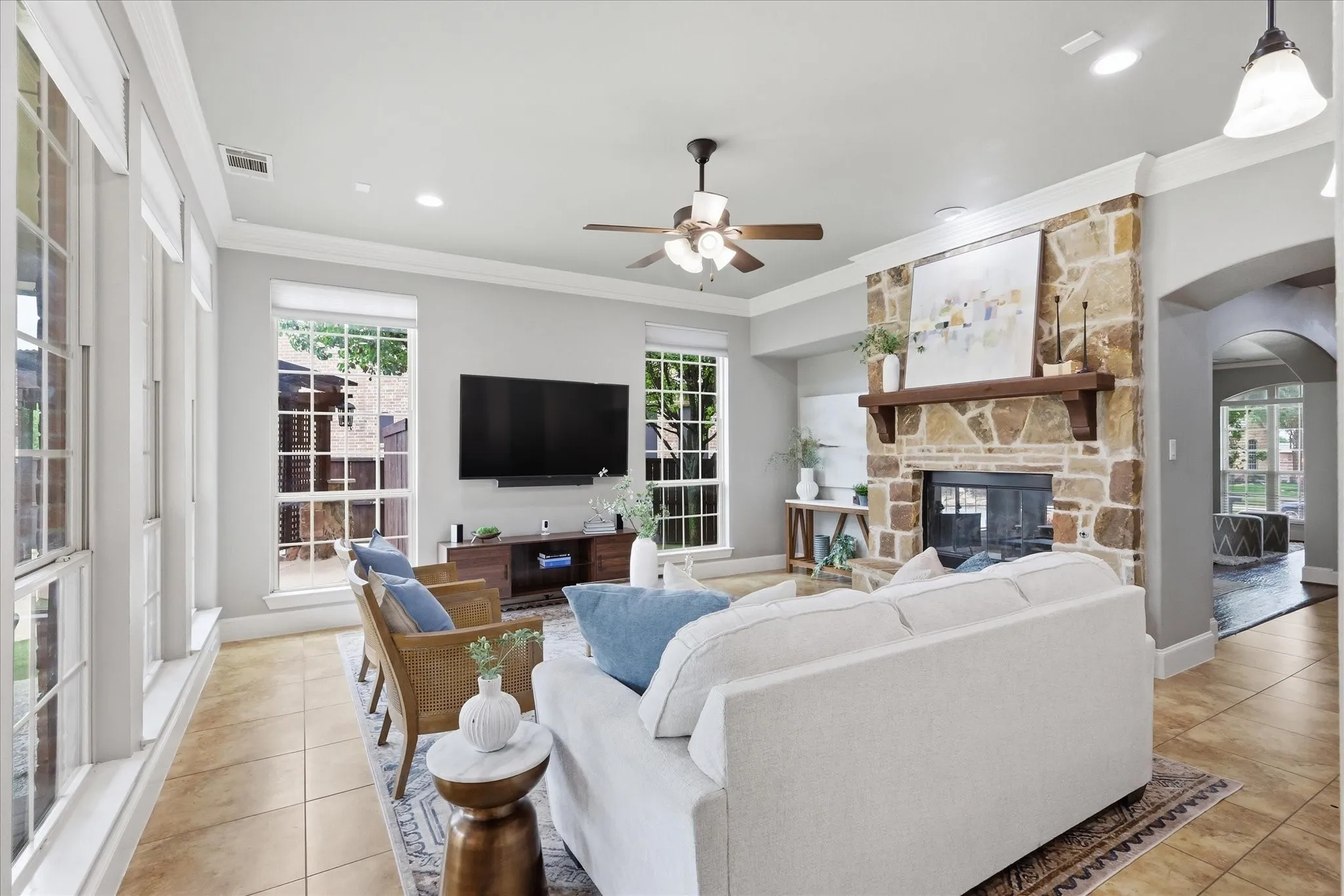 2253 Big Valley Circle, Allen, TX 75013 - Living room - Spacious living area featuring a floor-to-ceiling stone fireplace with a wood mantel, ample natural light from multiple windows, crown molding, and recessed lighting