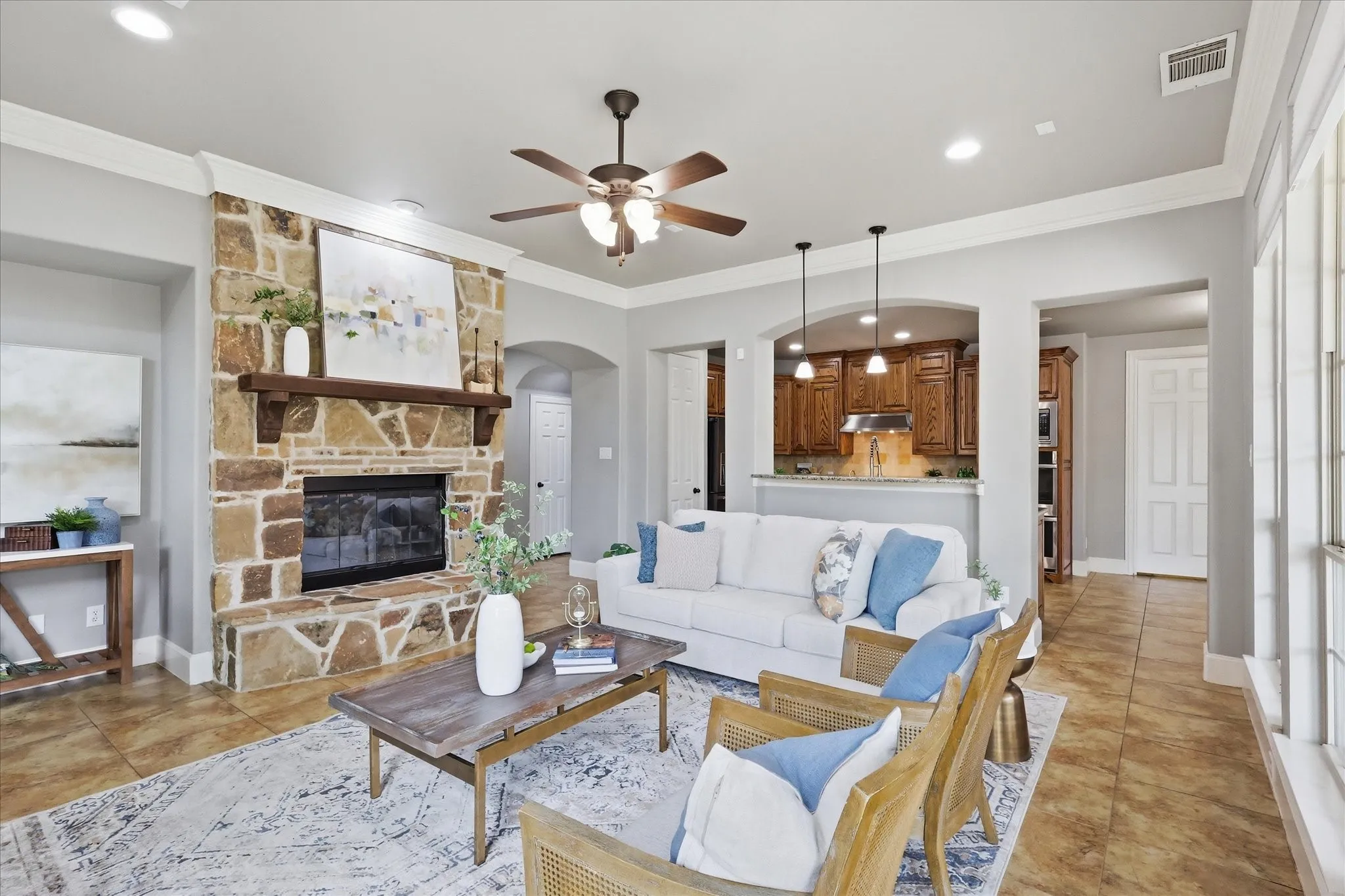 2253 Big Valley Circle, Allen, TX 75013 - Living room - Spacious living area featuring a floor-to-ceiling stone fireplace with a wood mantle, tile flooring, and a ceiling fan