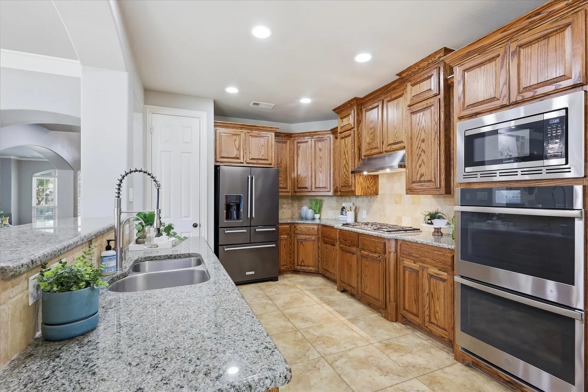 2253 Big Valley Circle, Allen, TX 75013 - Kitchen - spacious kitchen featuring extensive wood cabinetry, granite-style countertops, stainless steel appliances, and a double basin sink with a high-arch faucet