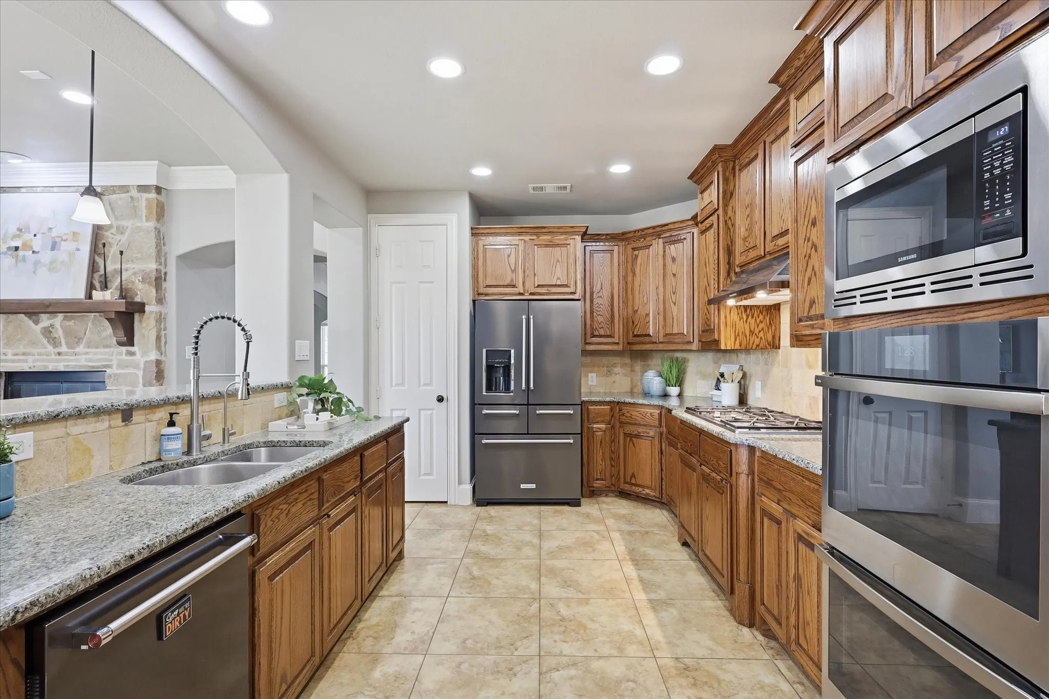2253 Big Valley Circle, Allen, TX 75013 - Kitchen - Kitchen featuring extensive wood cabinetry, granite countertops, tile flooring, and stainless steel appliances including a built-in microwave and double oven