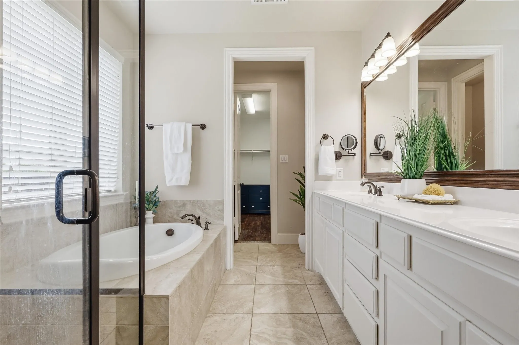 2253 Big Valley Circle, Allen, TX 75013 - Primary Bathroom - Primary bathroom featuring a dual vanity with white cabinetry and countertop, a framed mirror, a separate soaking tub with tile surround, and a glass-enclosed shower