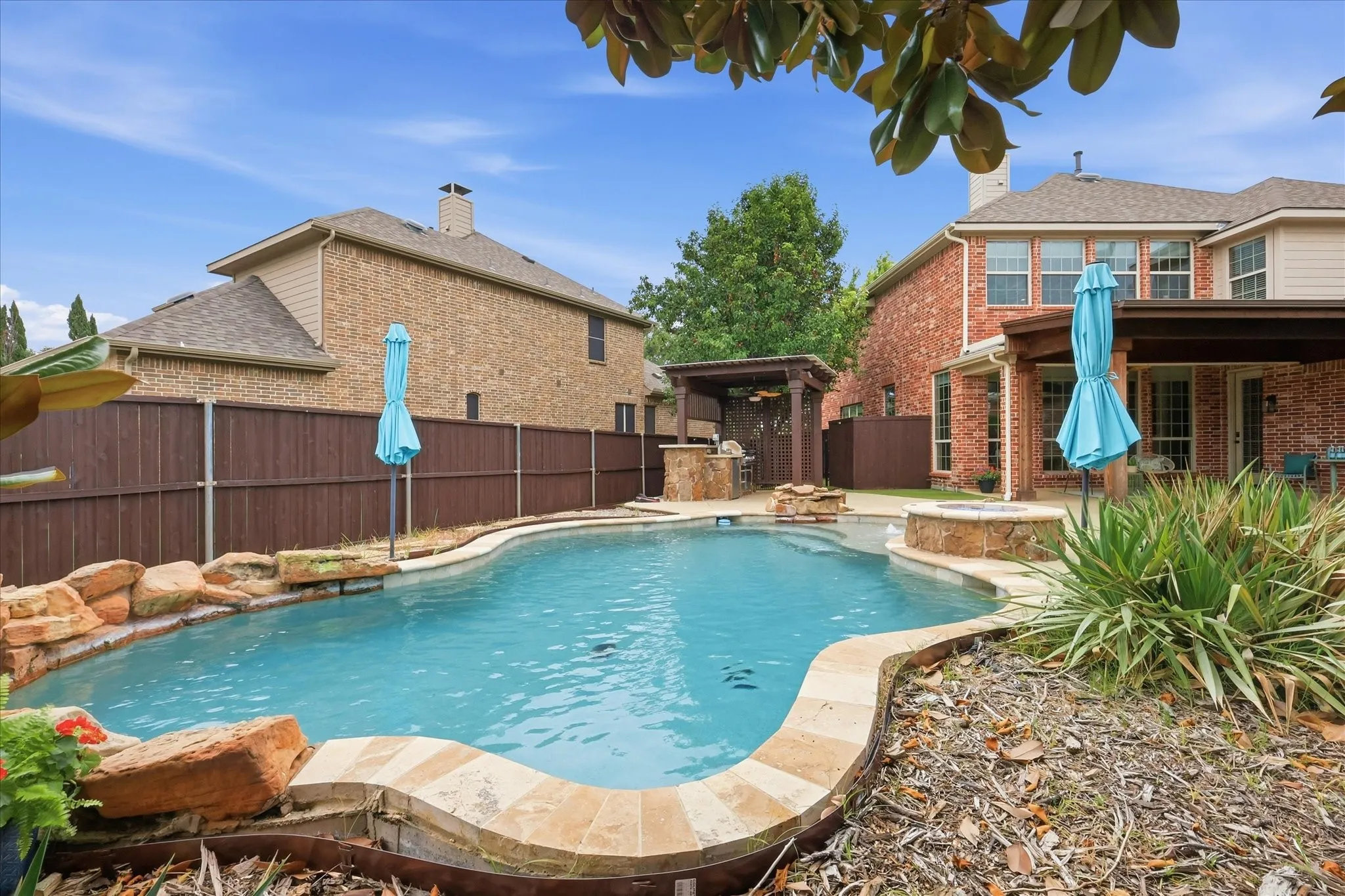 2253 Big Valley Circle, Allen, TX 75013 - Pool - Curved swimming pool with stone coping, an integrated stone spa, and a stone water feature
