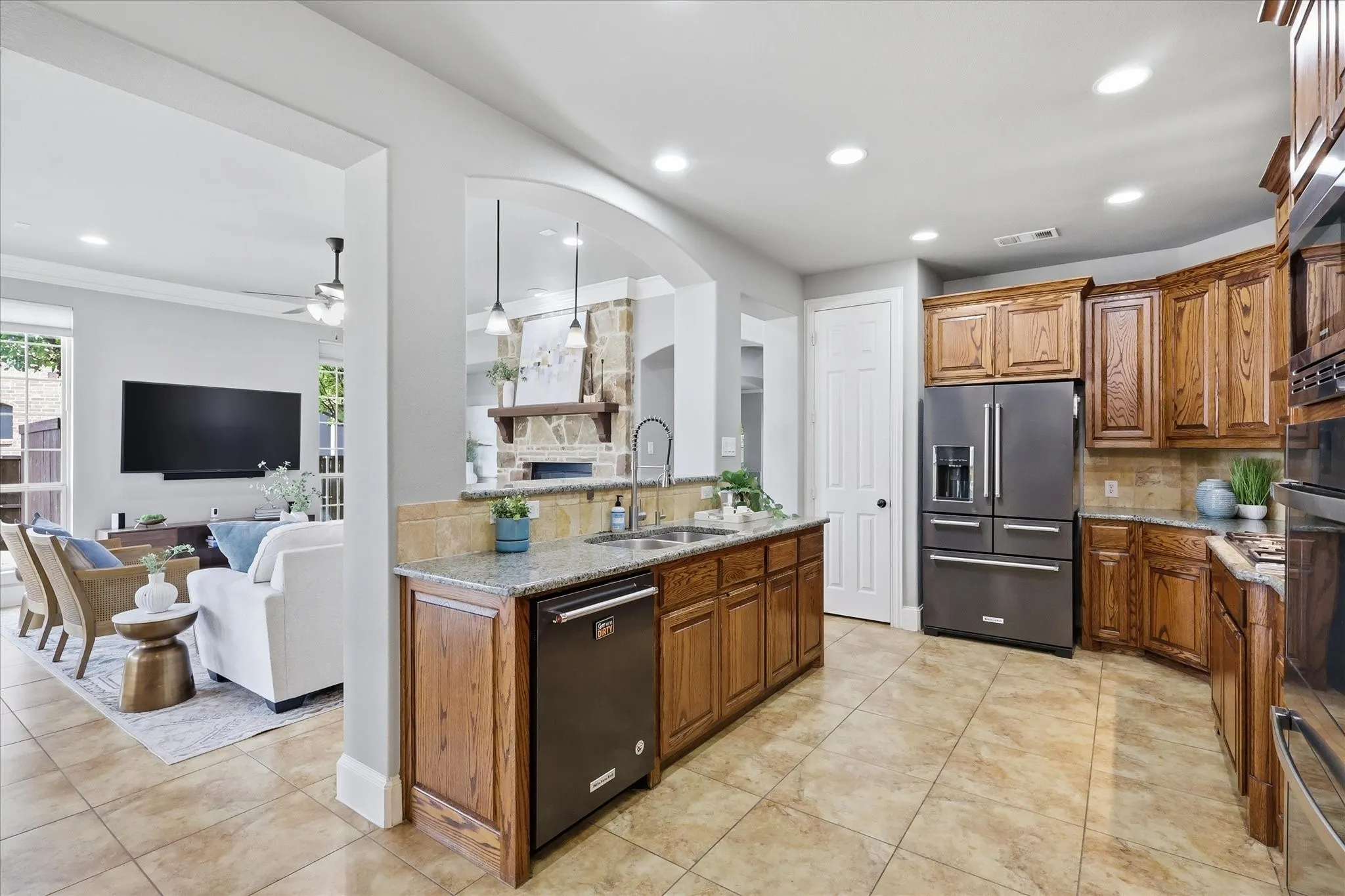 2253 Big Valley Circle, Allen, TX 75013 - kitchen - Kitchen featuring tile flooring, wood cabinetry, granite countertops, and stainless steel appliances, with an arched opening to the living area