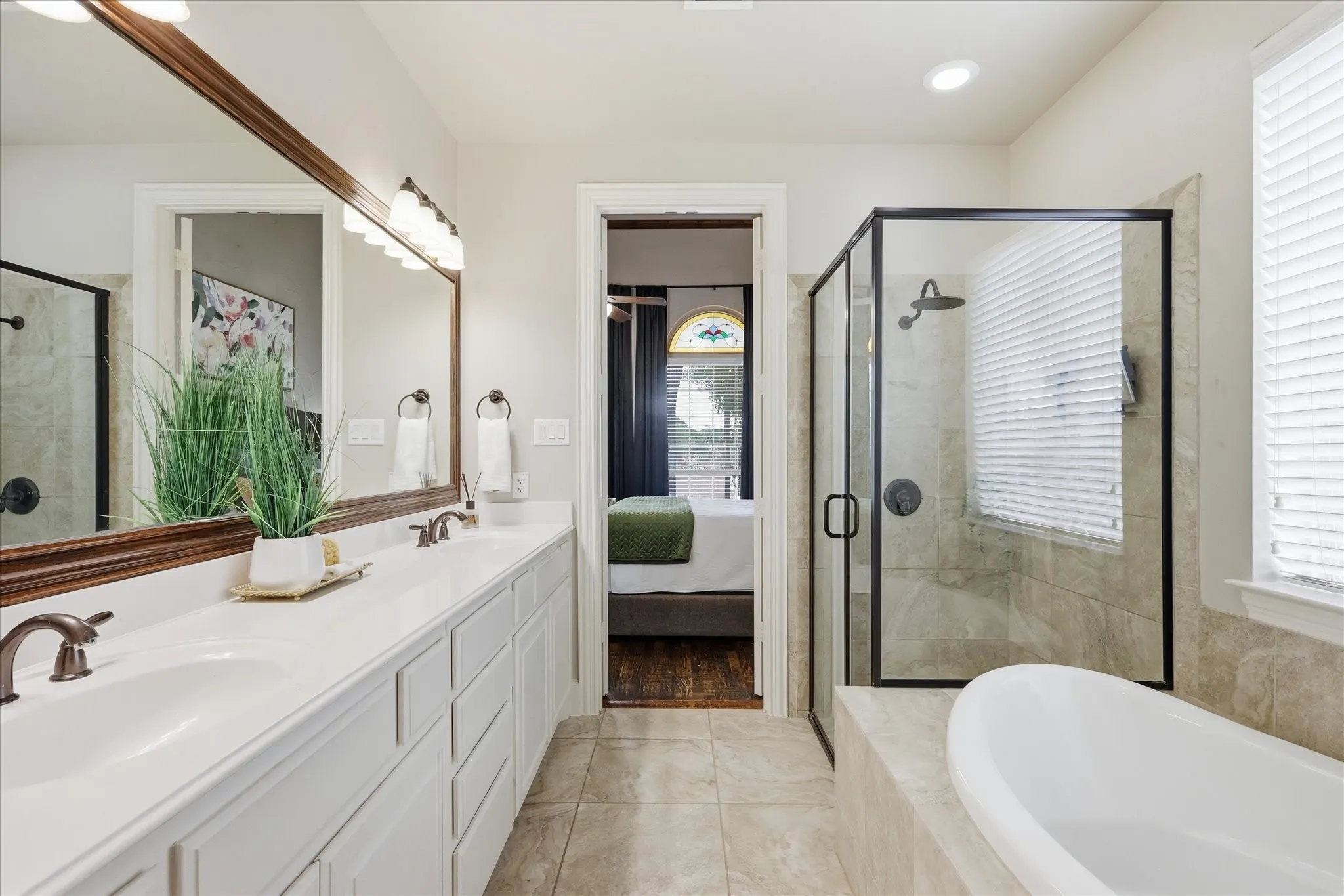 2253 Big Valley Circle, Allen, TX 75013 - Primary Bathroom - Primary bathroom featuring a dual vanity with white cabinetry and countertop, a large framed mirror with sconce lighting, a glass-enclosed shower with tile surround, and a separate soaking tub