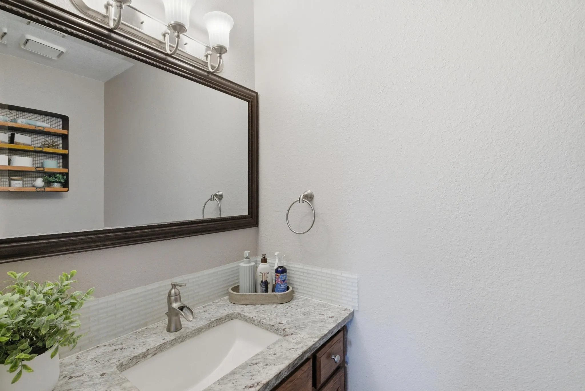 Bathroom vanity featuring a granite countertop, undermount sink, and brushed nickel faucet