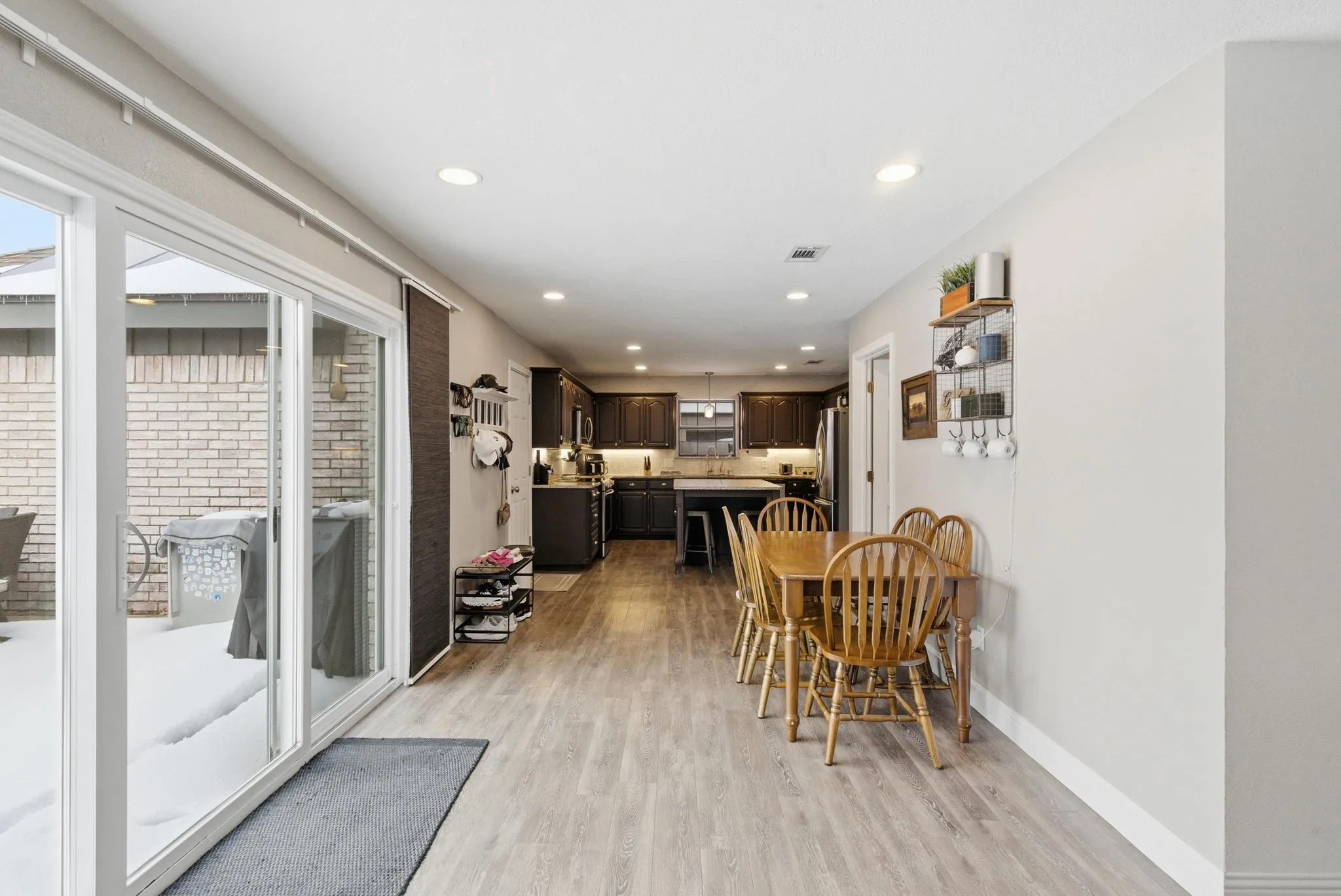 Open-concept living space with light wood-finish flooring, recessed lighting, and sliding glass patio doors