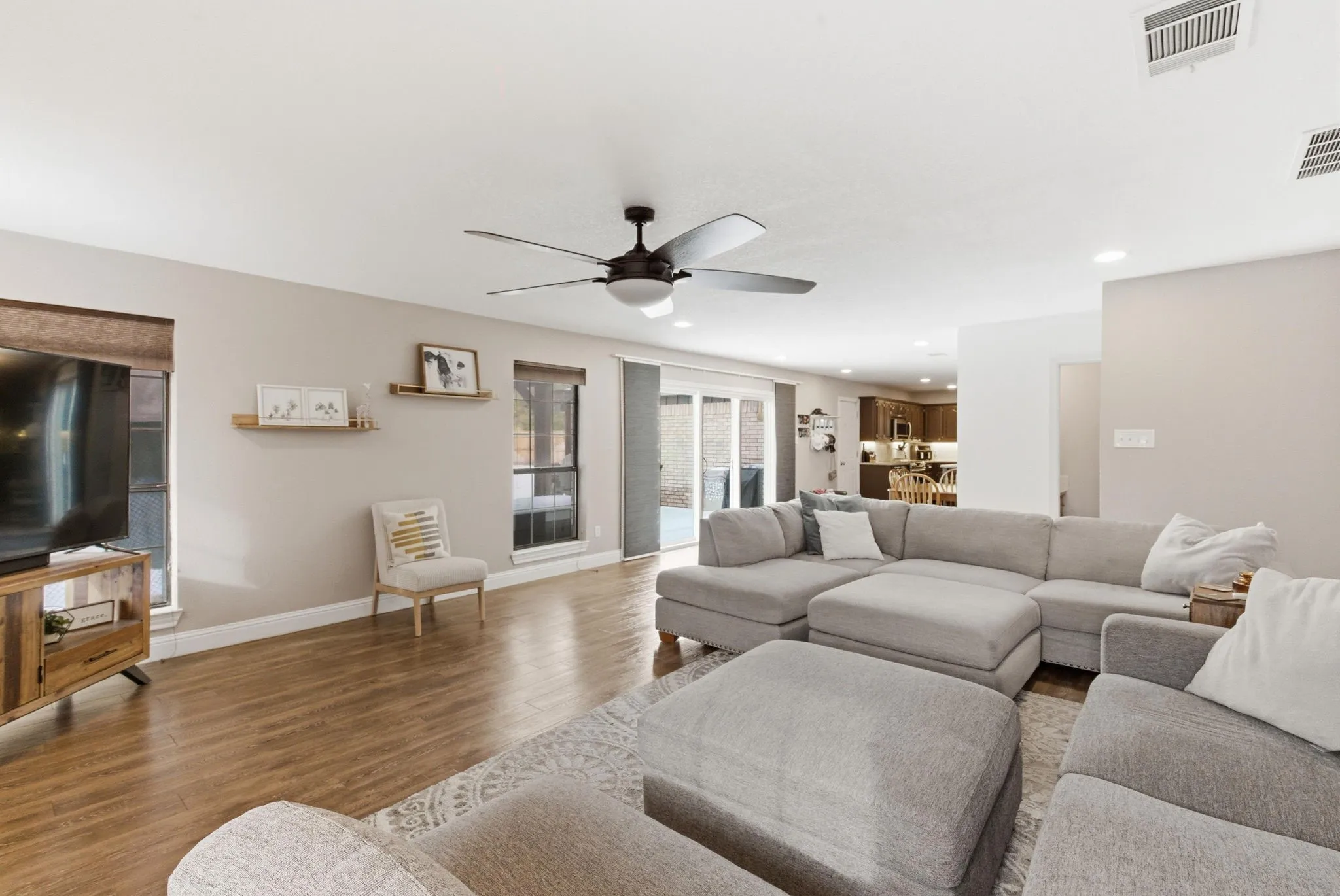 Expansive living area featuring wood-finish flooring, recessed lighting, and a dark-toned ceiling fan