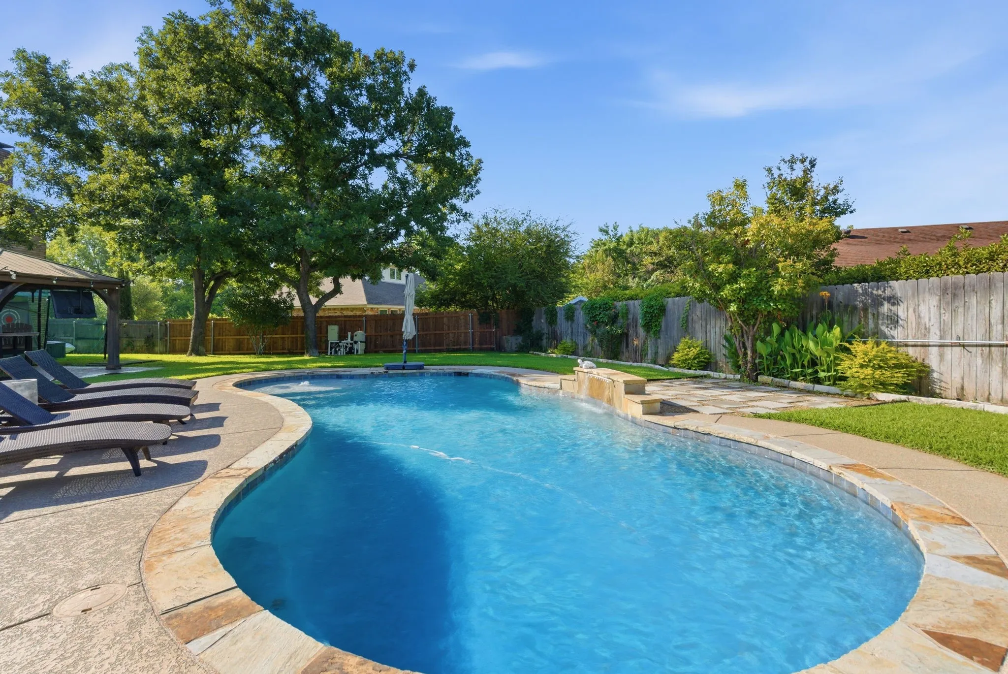 Custom-shaped swimming pool with a natural stone coping and integrated waterfall feature
