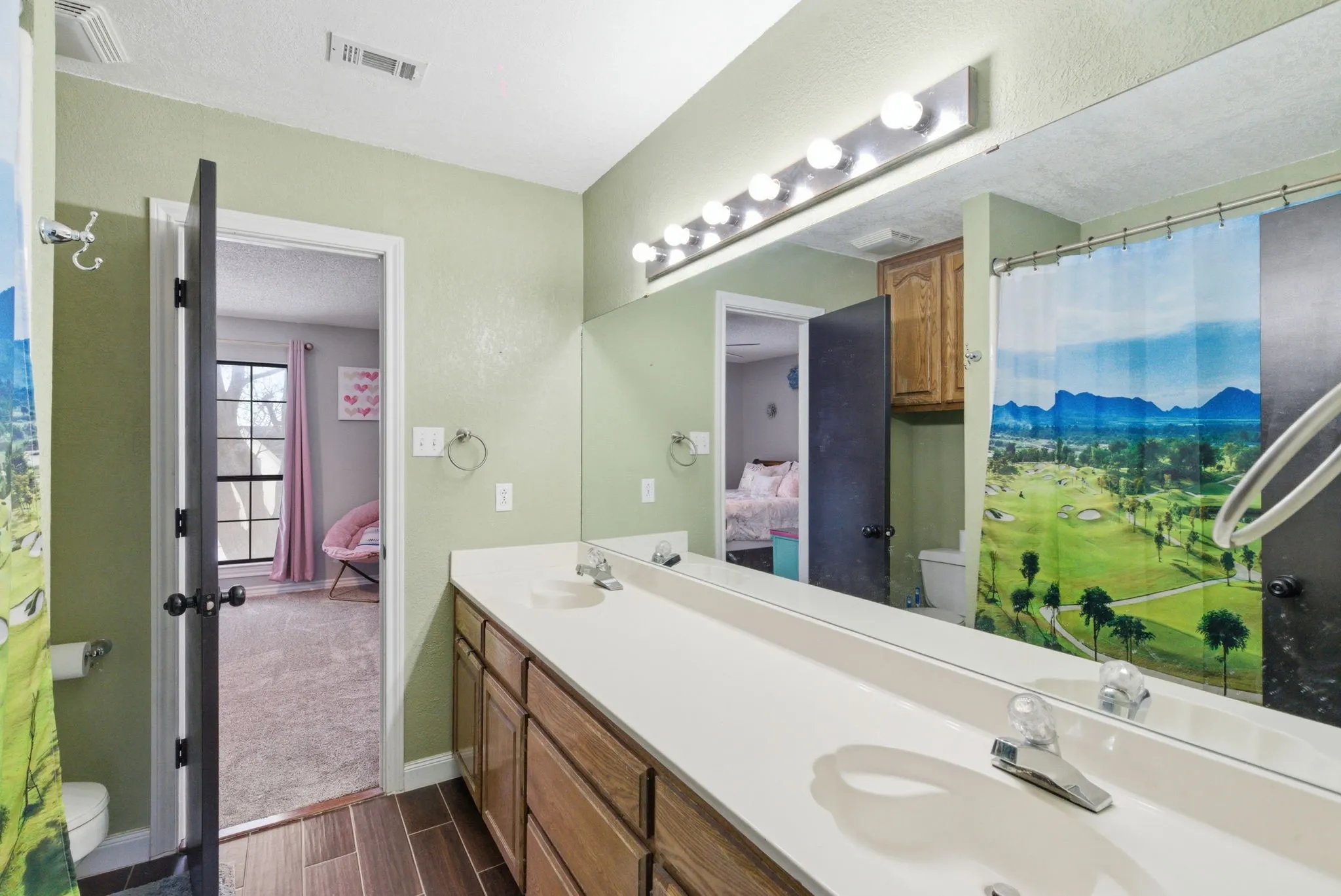 Bathroom featuring a double vanity with ample counter space, wood-finish cabinetry, and a large wall-mounted mirror