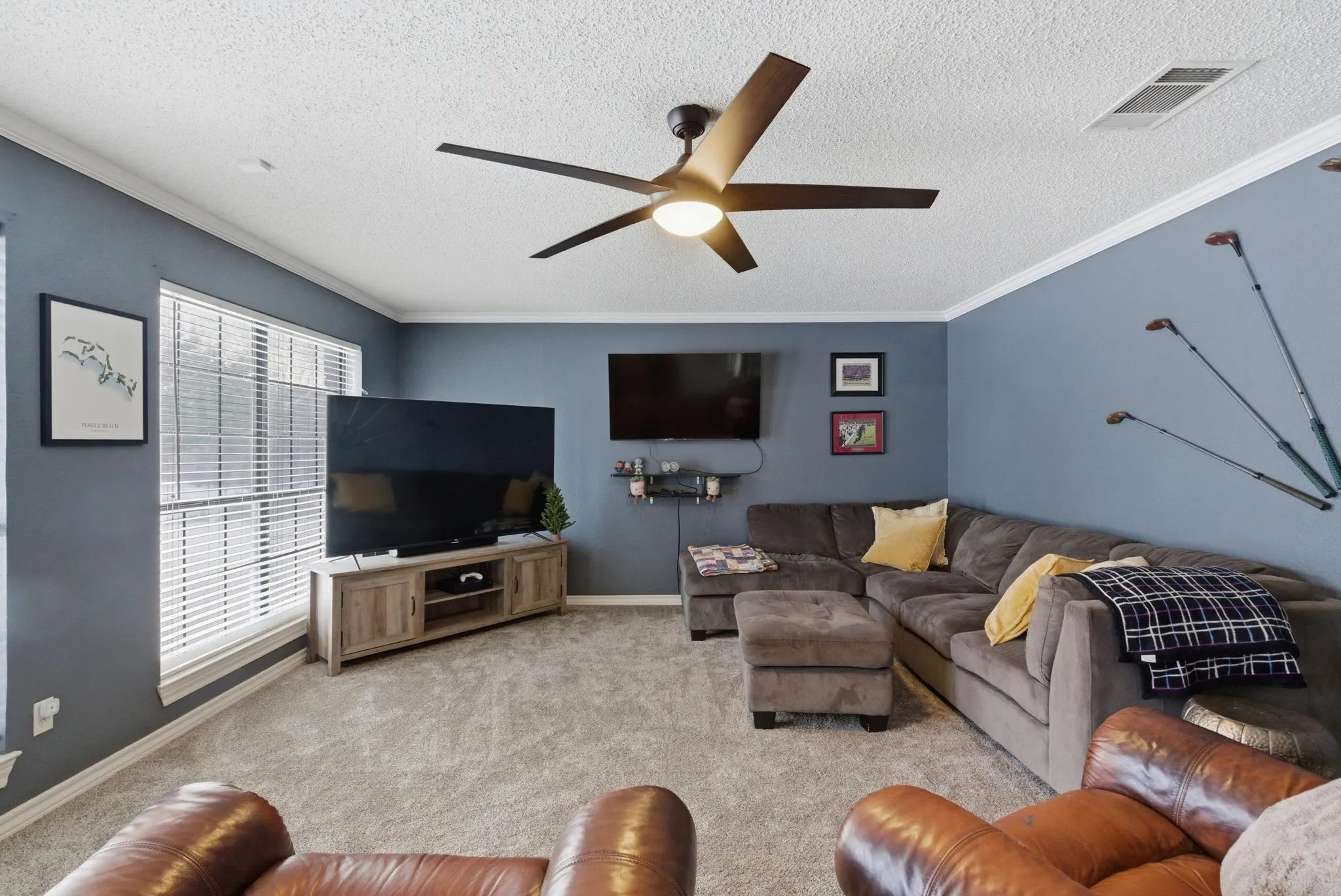Living area featuring a ceiling fan with integrated lighting, textured ceiling, and crown molding
