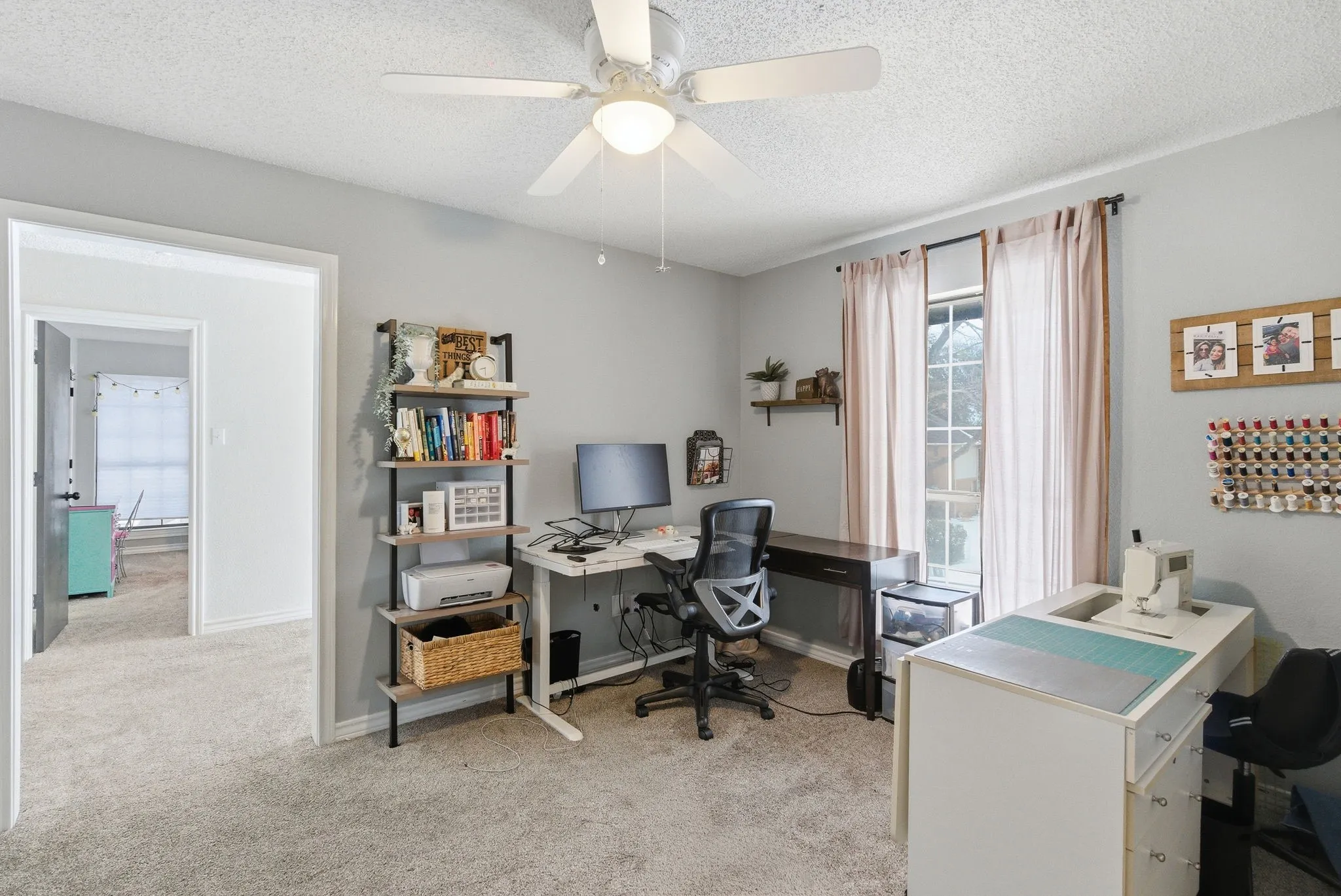 Carpeted room featuring a ceiling fan with integrated lighting, a window with vertical blinds, and a built-in floating shelf