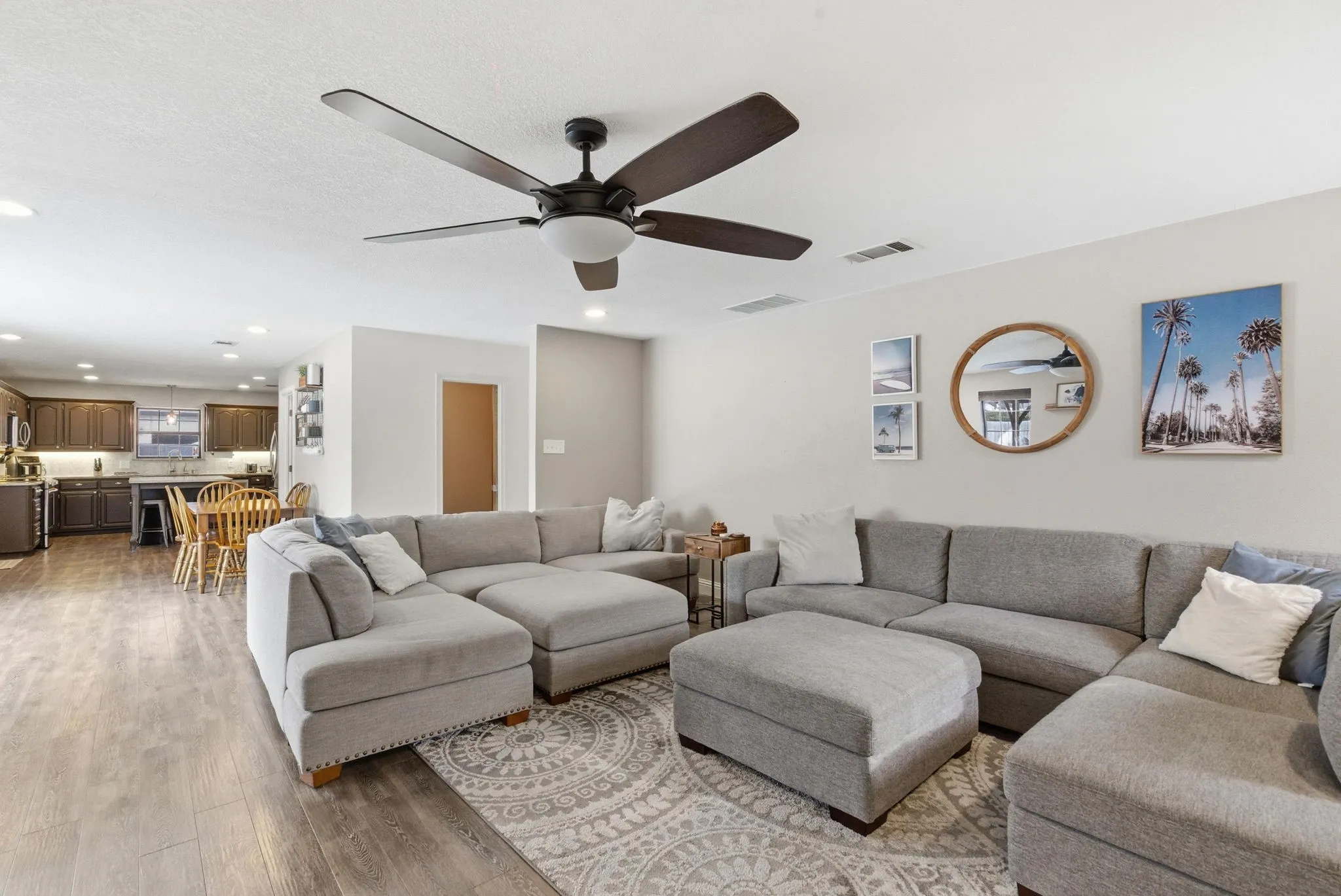 Open-concept living space featuring wood-finish flooring, a contemporary ceiling fan, and recessed lighting