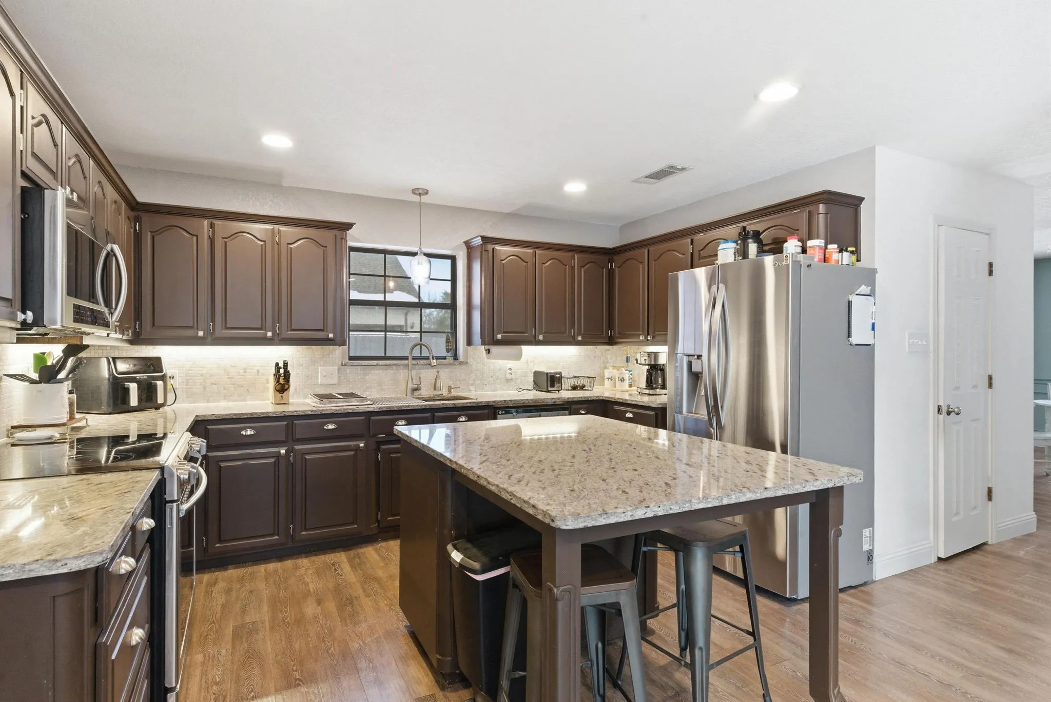 Spacious kitchen featuring dark wood cabinetry, light-toned countertops, and wood-finish flooring