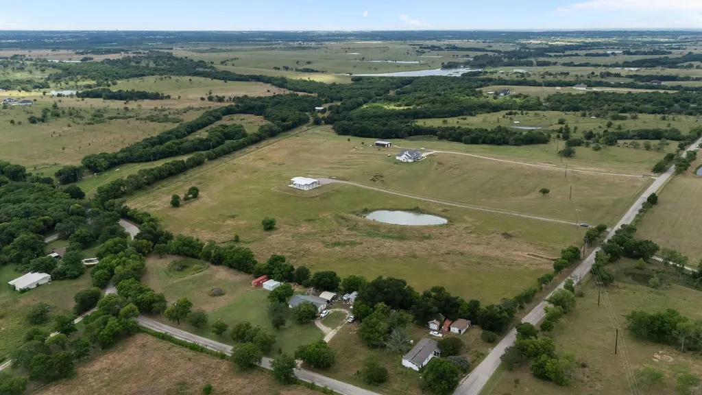 Expansive rural property featuring multiple pastures, a large pond, and mature tree lines