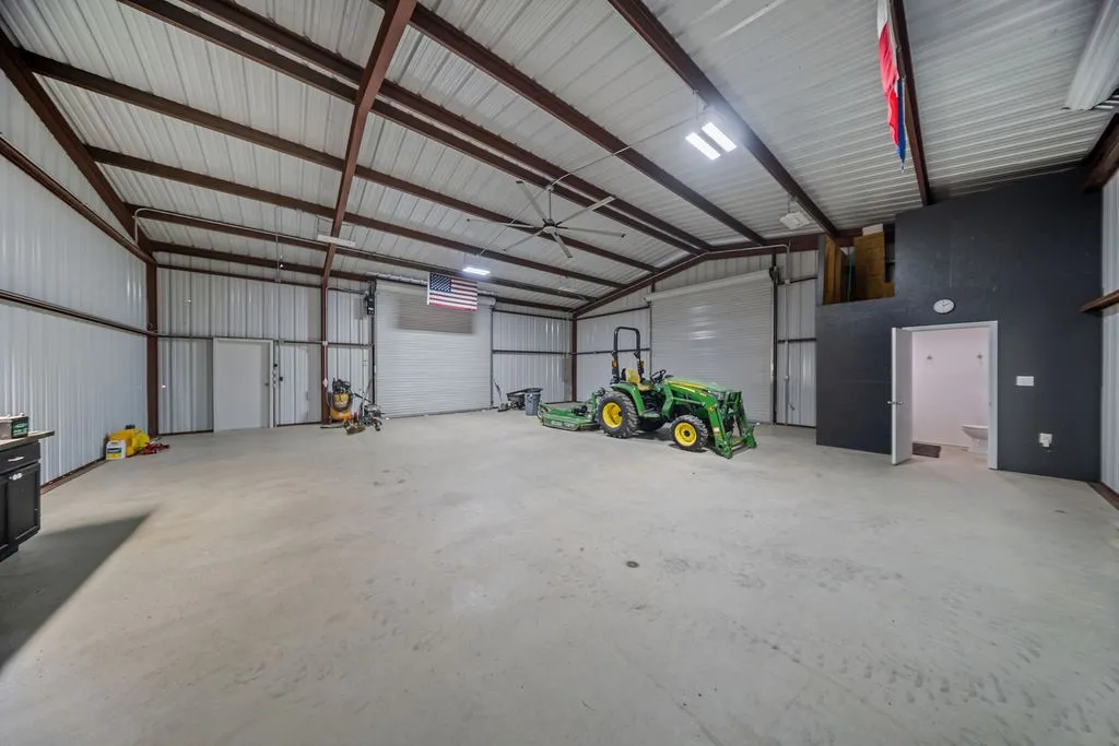 Spacious metal construction building featuring a high-pitched roof, exposed support beams, and a concrete floor