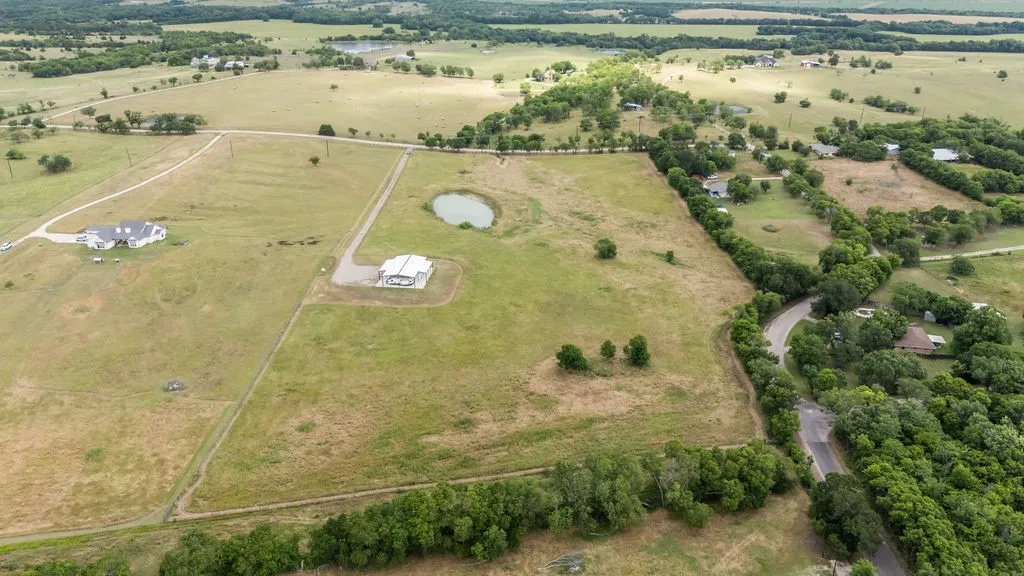 Expansive property featuring a private pond, long paved driveway, and mature landscaping