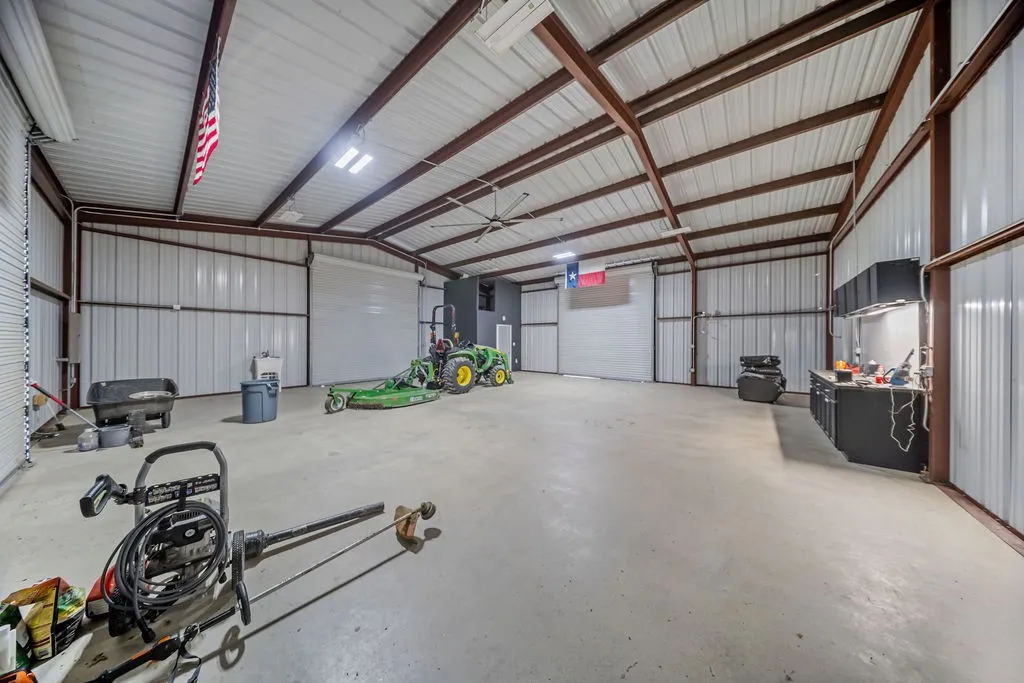 Expansive metal building featuring a concrete floor, exposed steel beam construction, corrugated metal walls, and multiple overhead doors