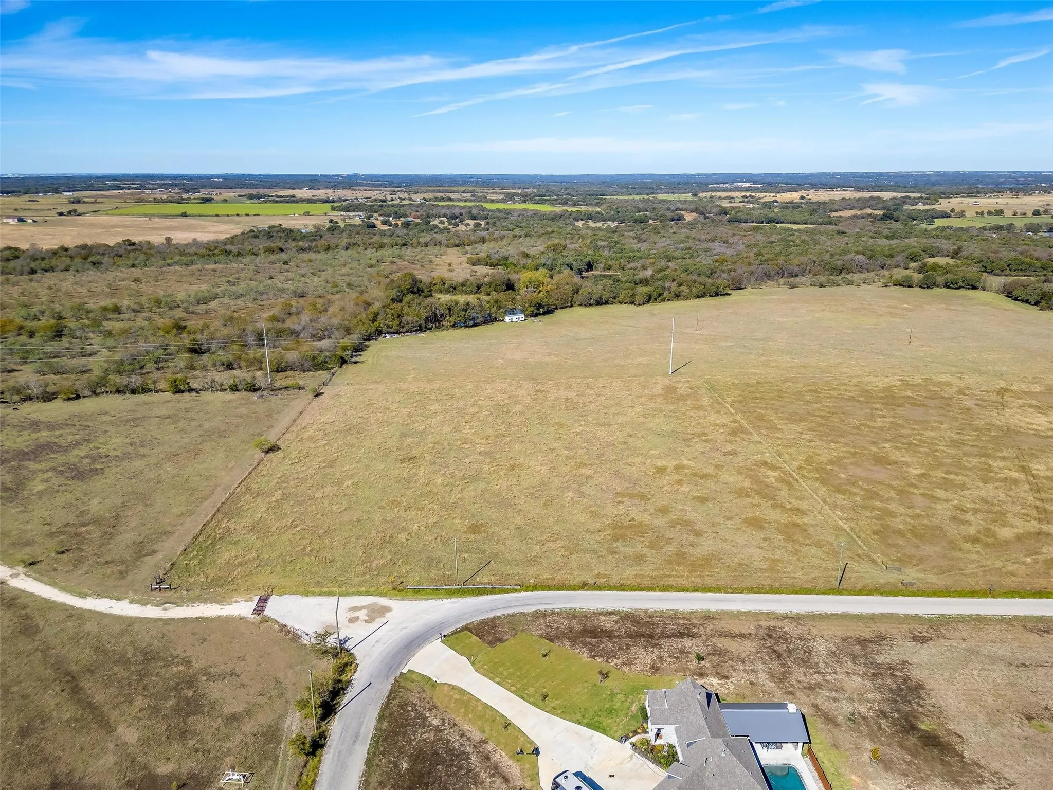 Expansive rural landscape featuring a mix of open fields and natural tree lines