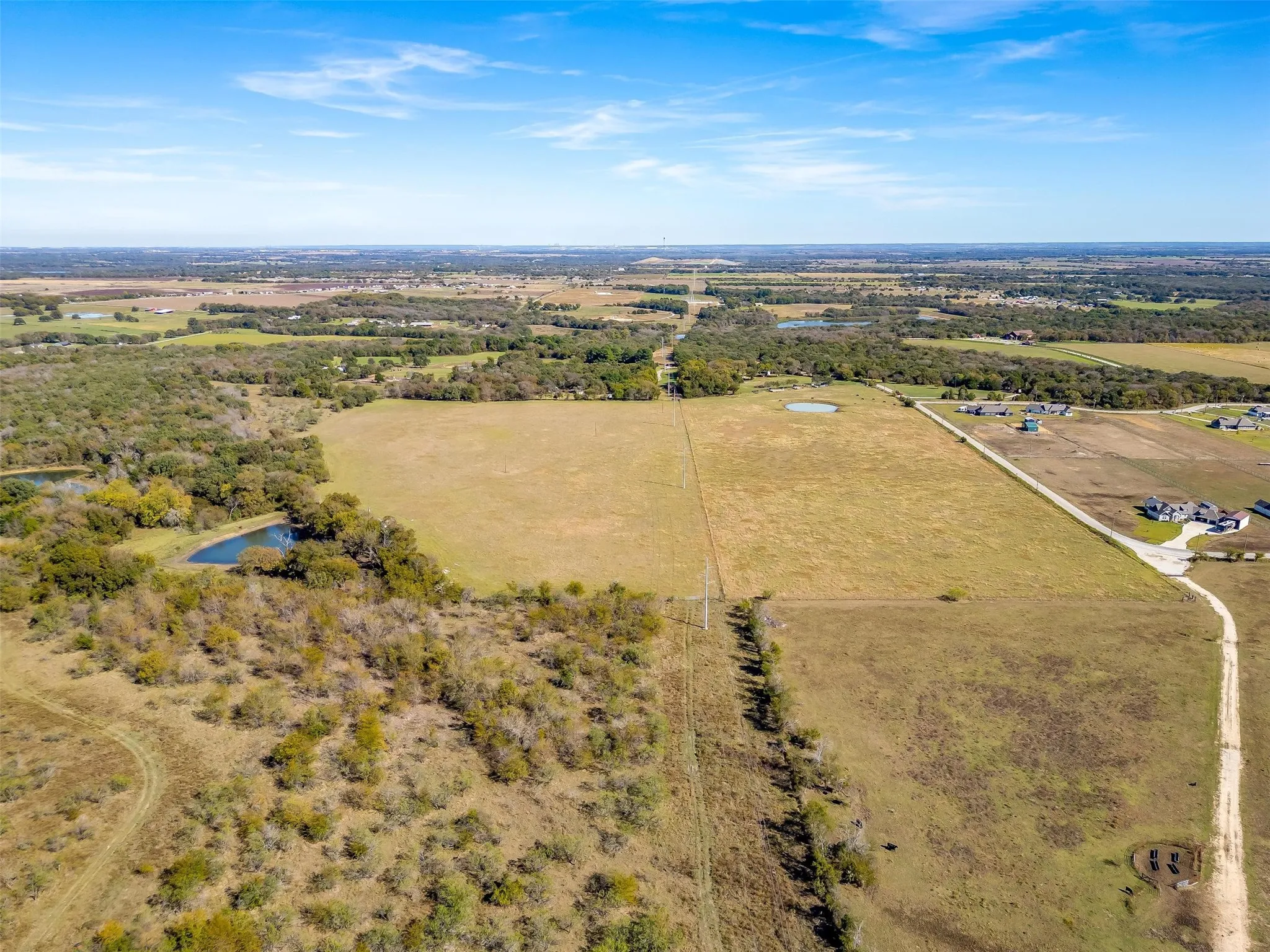 Expansive acreage featuring multiple open fields, wooded areas, and two ponds