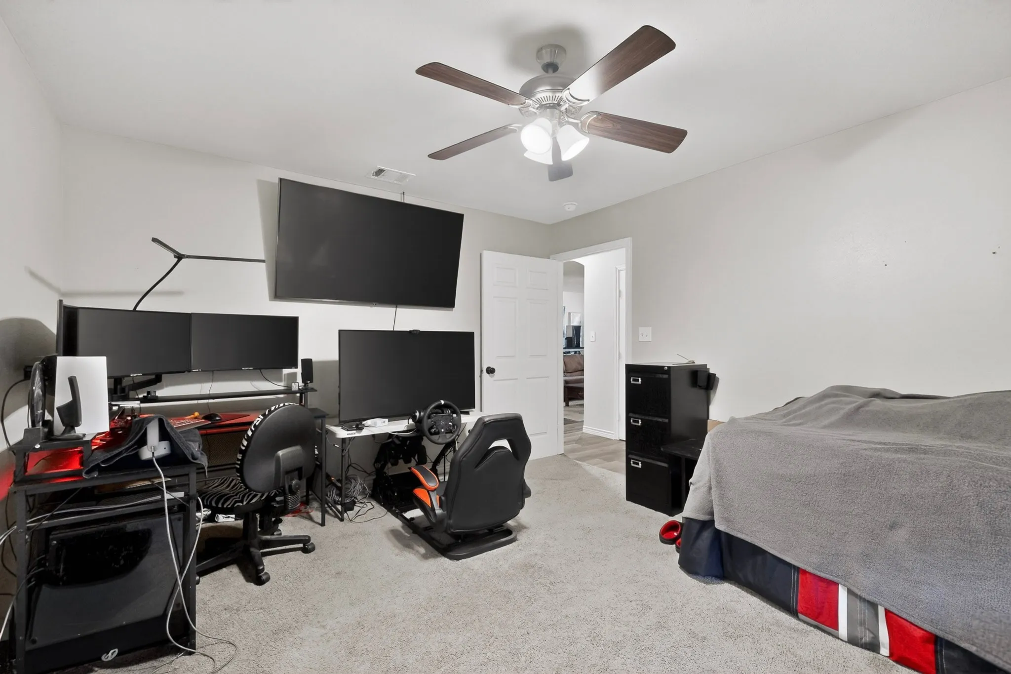 Spacious room featuring light gray walls, light gray carpet flooring, and a ceiling fan with integrated lighting
