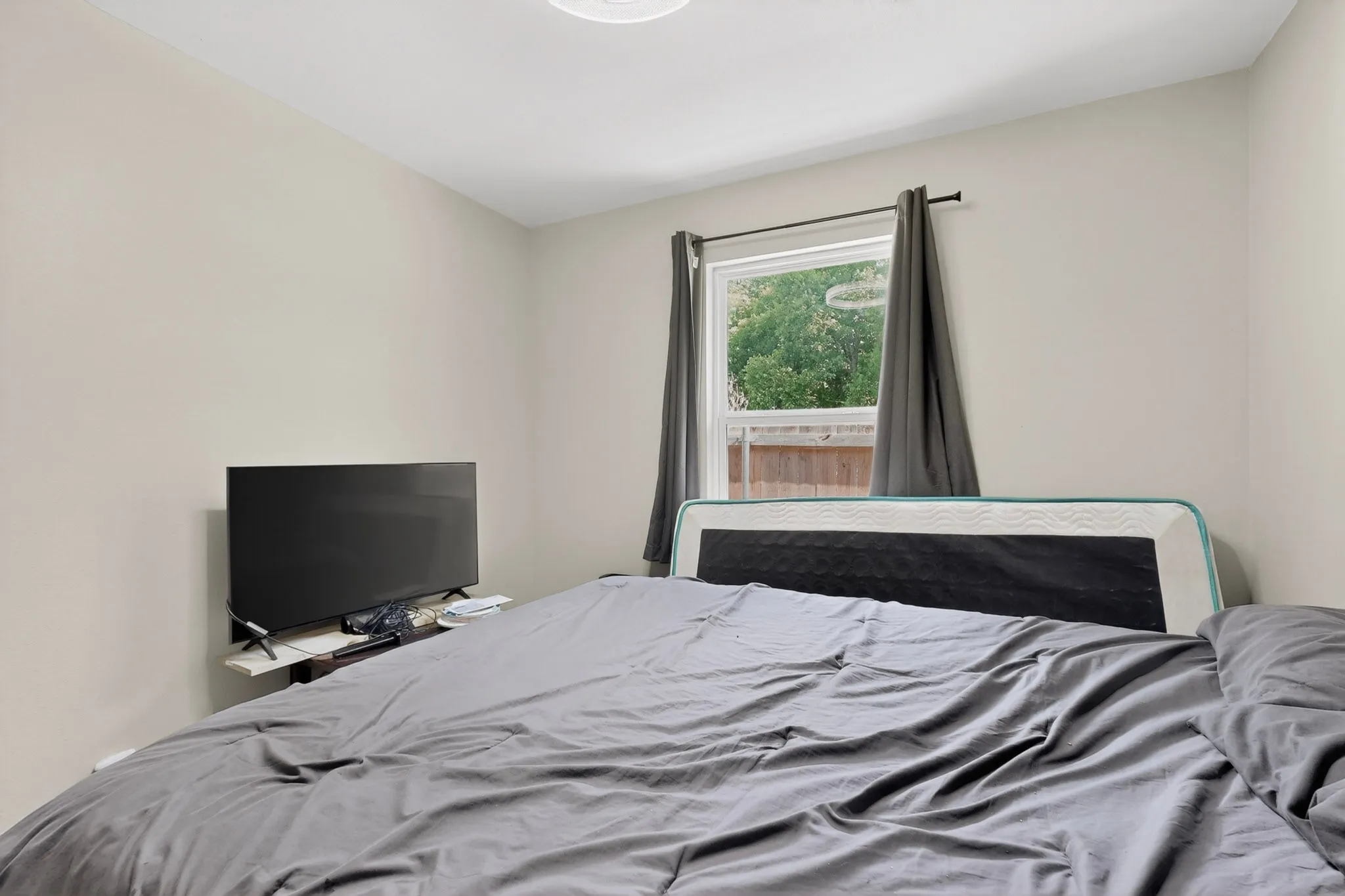Neutral-toned room featuring a single window with dark drapery