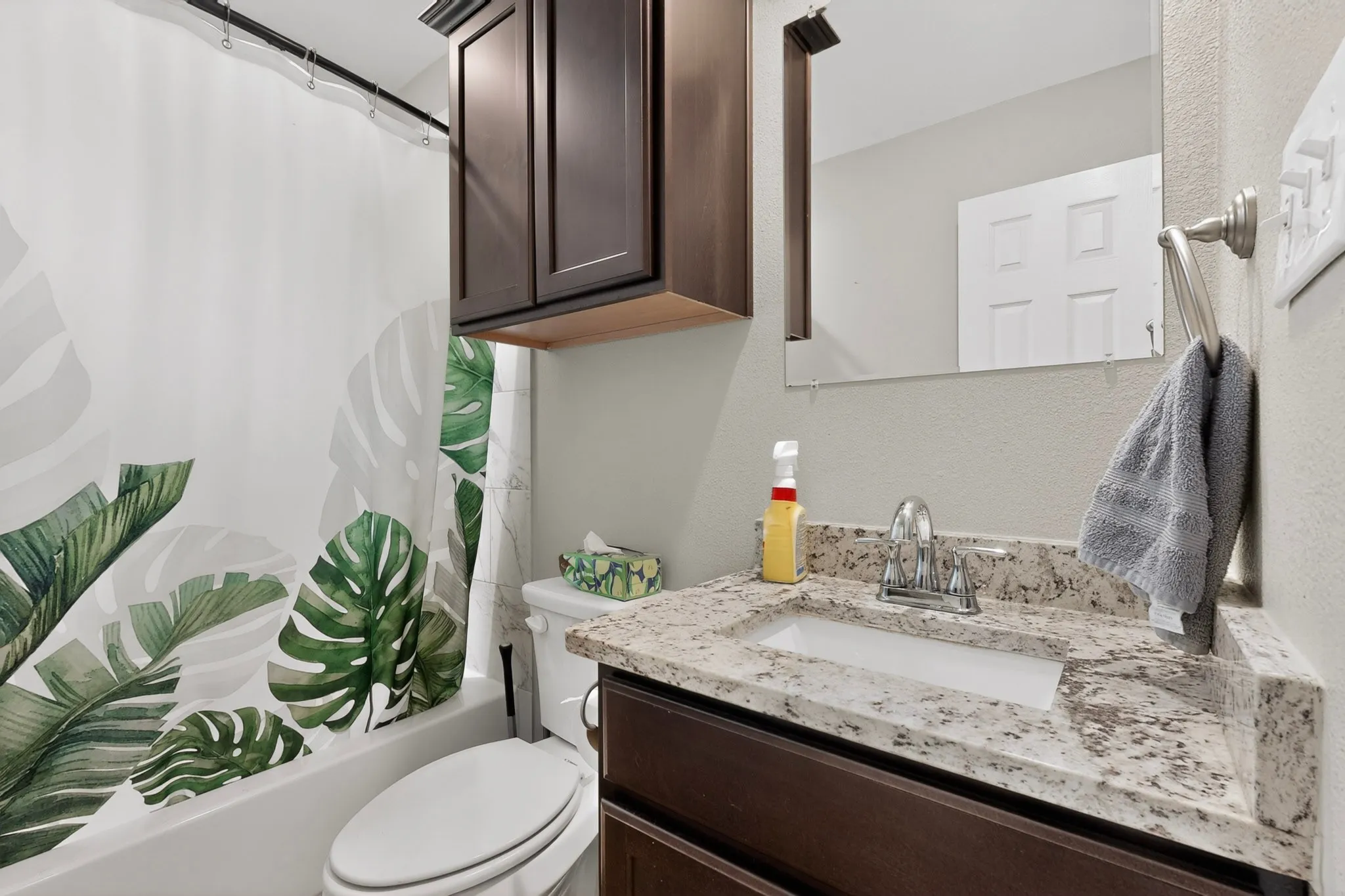 Bathroom featuring a granite-look countertop vanity with an undermount sink, brushed nickel faucet, and a wall-mounted mirror