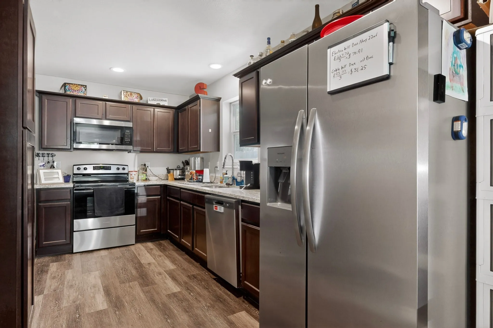 Kitchen featuring wood-finish flooring, dark wood cabinetry, stainless steel appliances, and recessed lighting